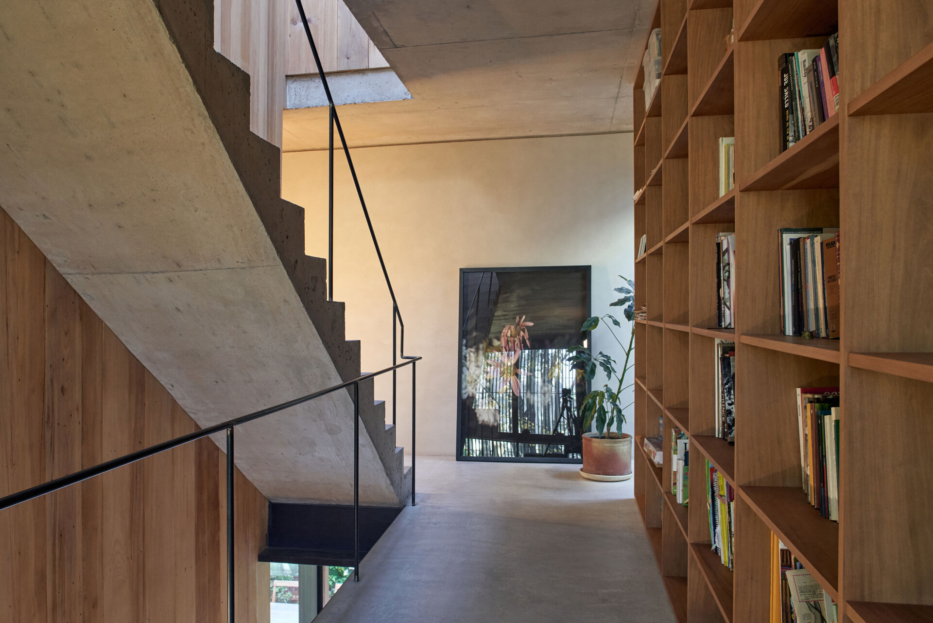 Concrete stairs with a black metal handrail add a bold, minimal element to the open interior.