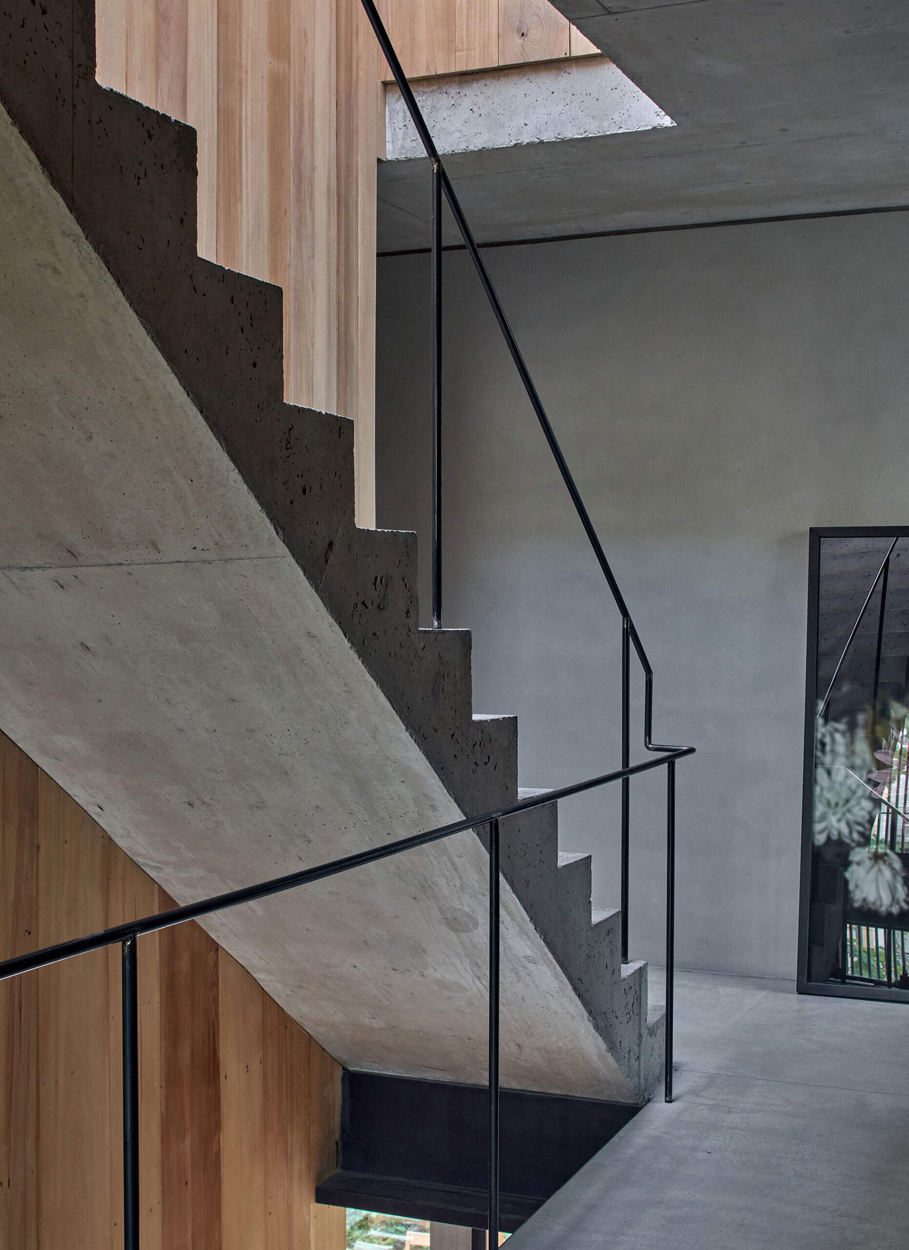 Concrete stairs with a black metal handrail add a bold, minimal element to the open interior.