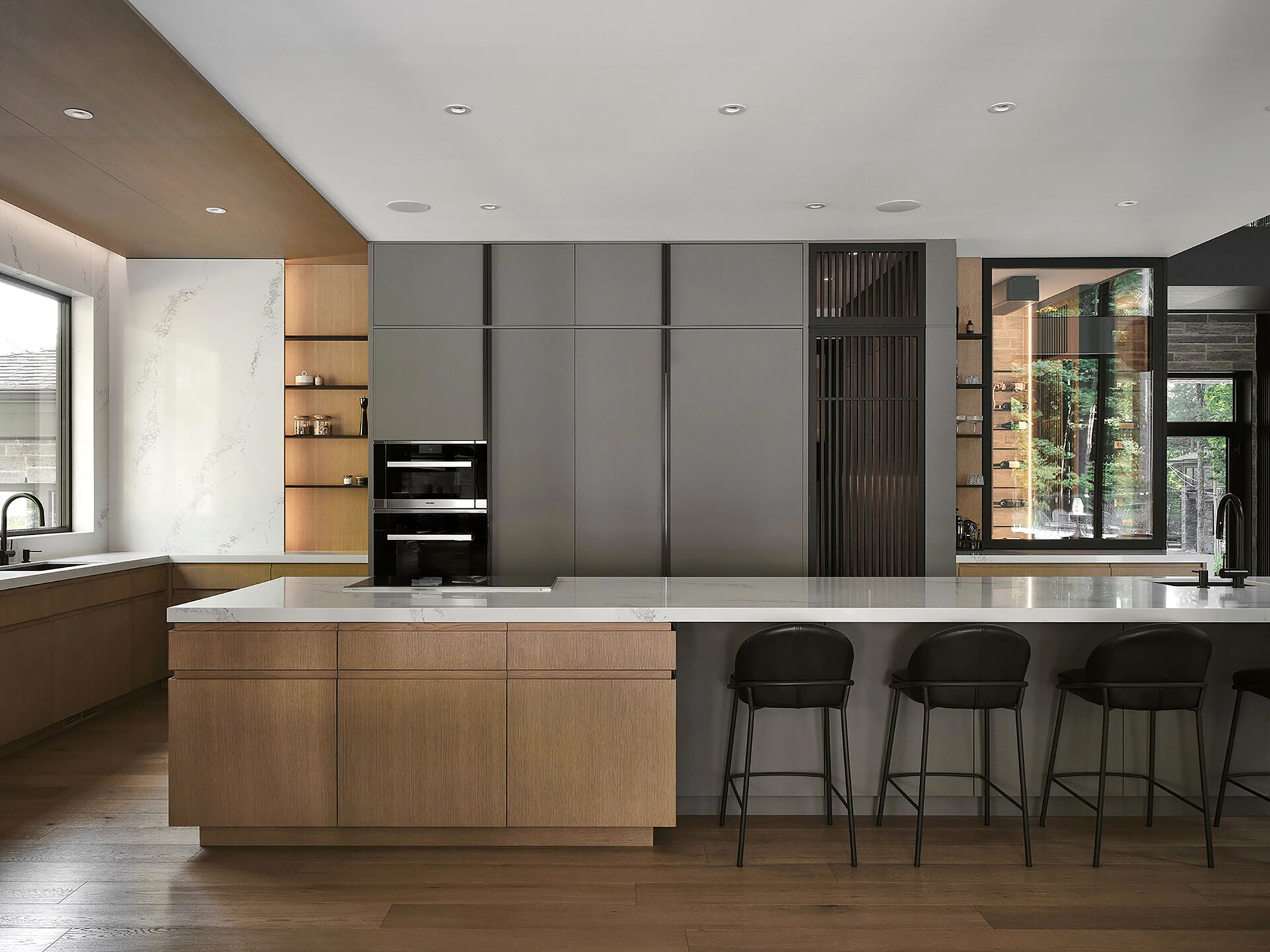 Pale grey cabinetry, natural wood, and quartz countertops give this modern kitchen a warm contemporary look with clean architectural styling.