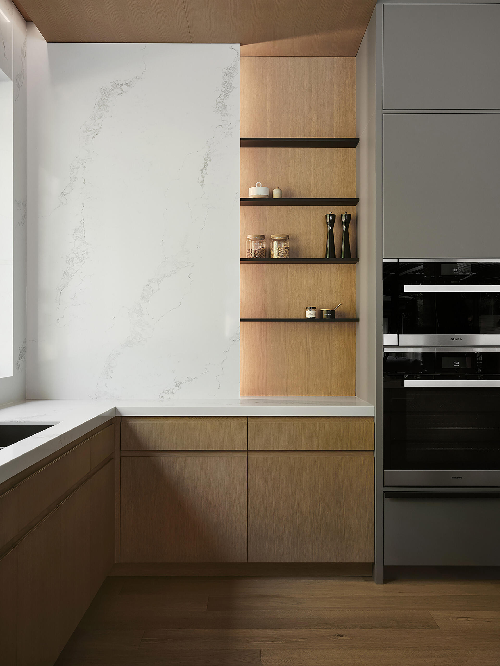 Pale grey cabinetry, natural wood, and quartz countertops give this modern kitchen a warm contemporary look with clean architectural styling.