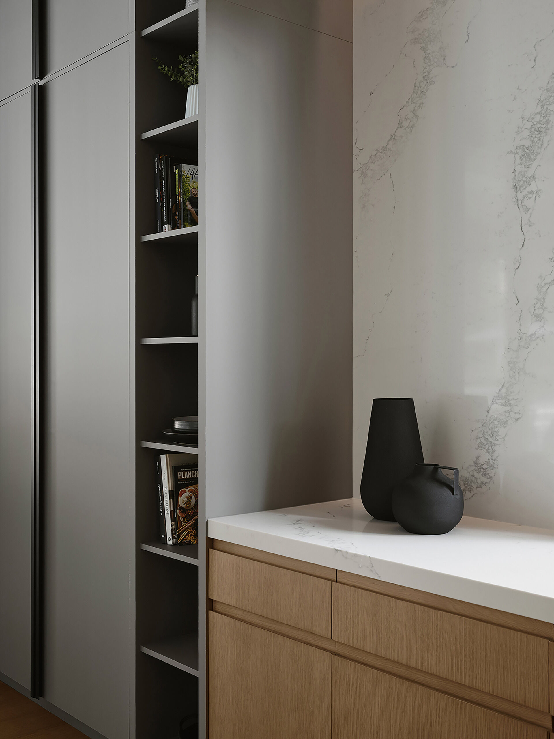 Pale grey cabinetry, natural wood, and quartz countertops give this modern kitchen a warm contemporary look with clean architectural styling.