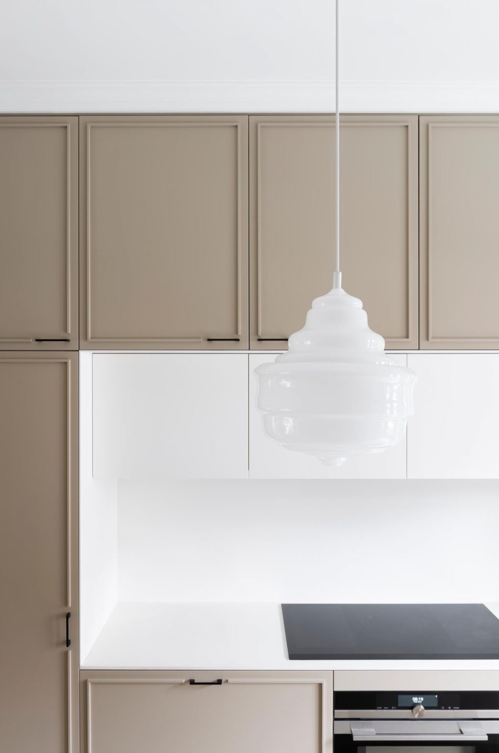 This modern London kitchen pairs a curved white island with terrazzo floors, black steel framing, and geometric glass architecture.