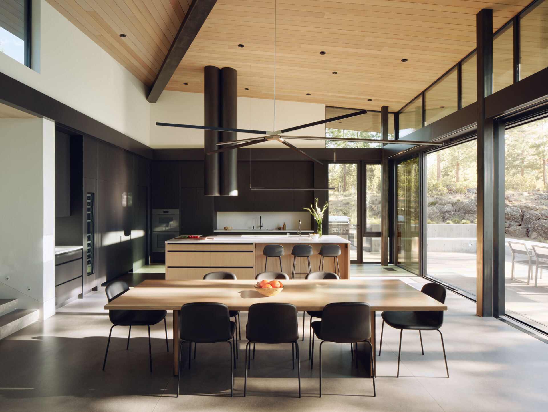 Warm wood cabinetry, concrete floors, and forest views give this modern Oregon kitchen a clean yet welcoming atmosphere.