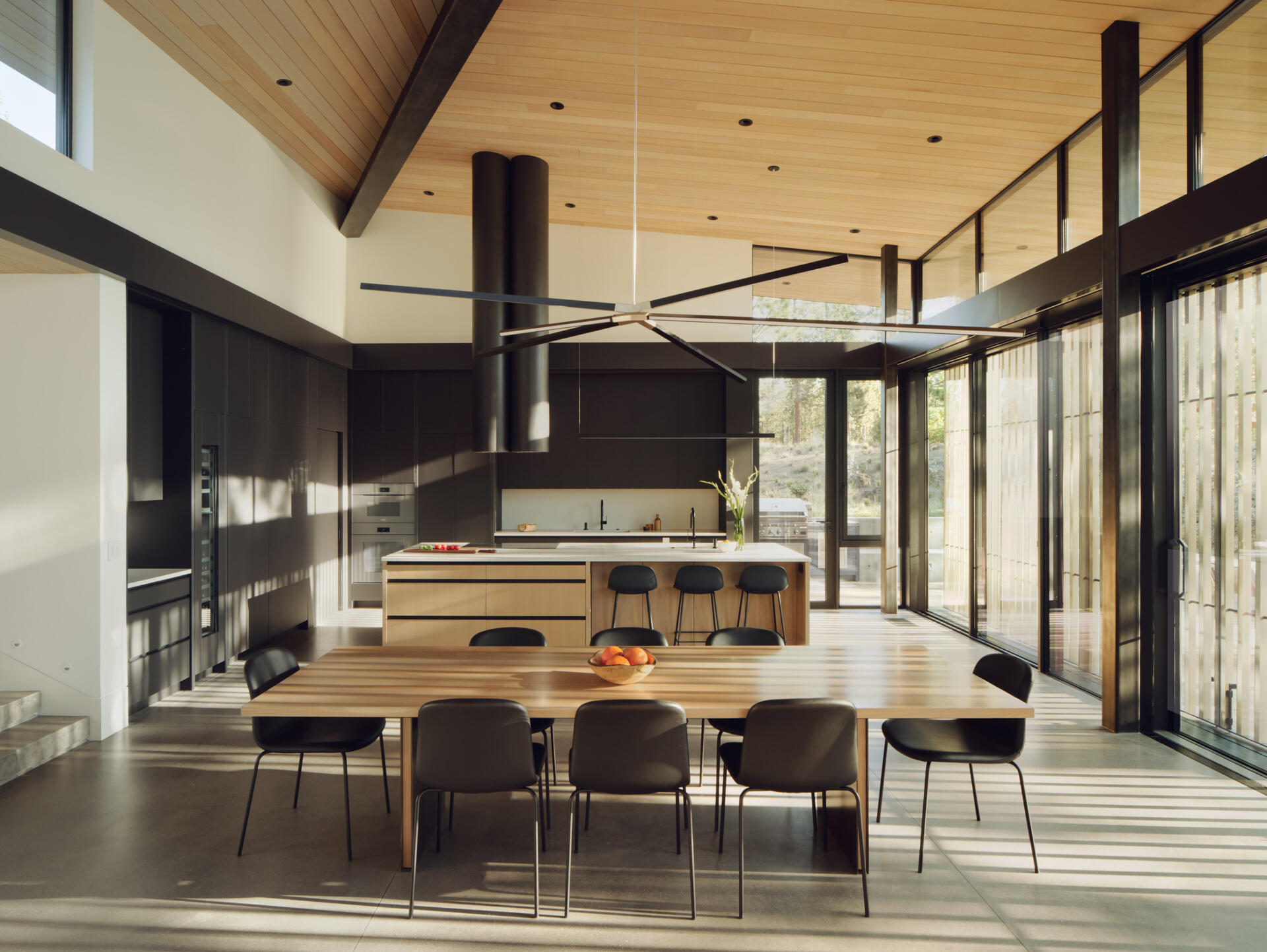 Warm wood cabinetry, concrete floors, and forest views give this modern Oregon kitchen a clean yet welcoming atmosphere.