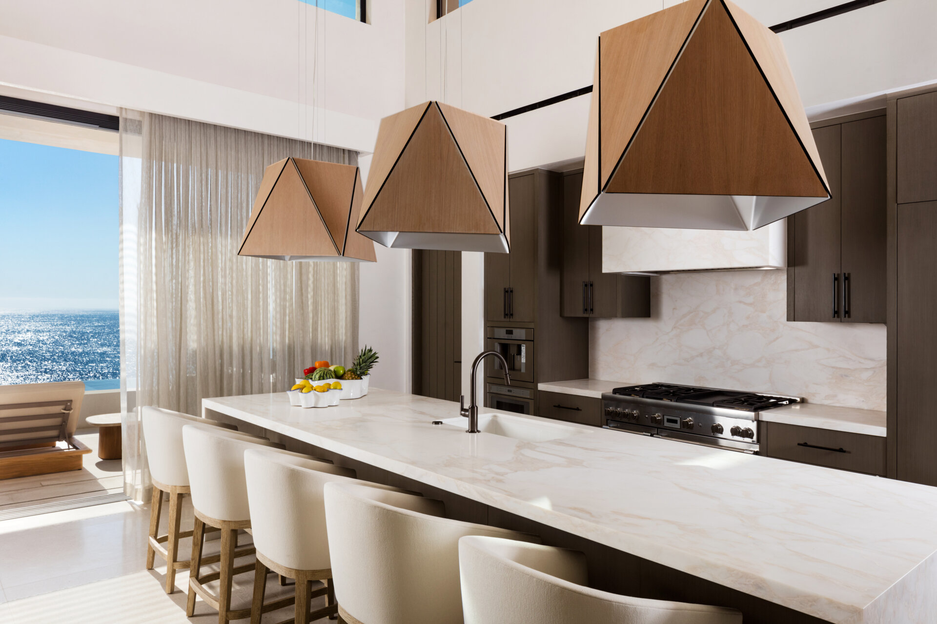Warm woods, sculptural Cerno Calx pendants, and layered textures give this luxury Cabo kitchen a relaxed but elevated atmosphere.