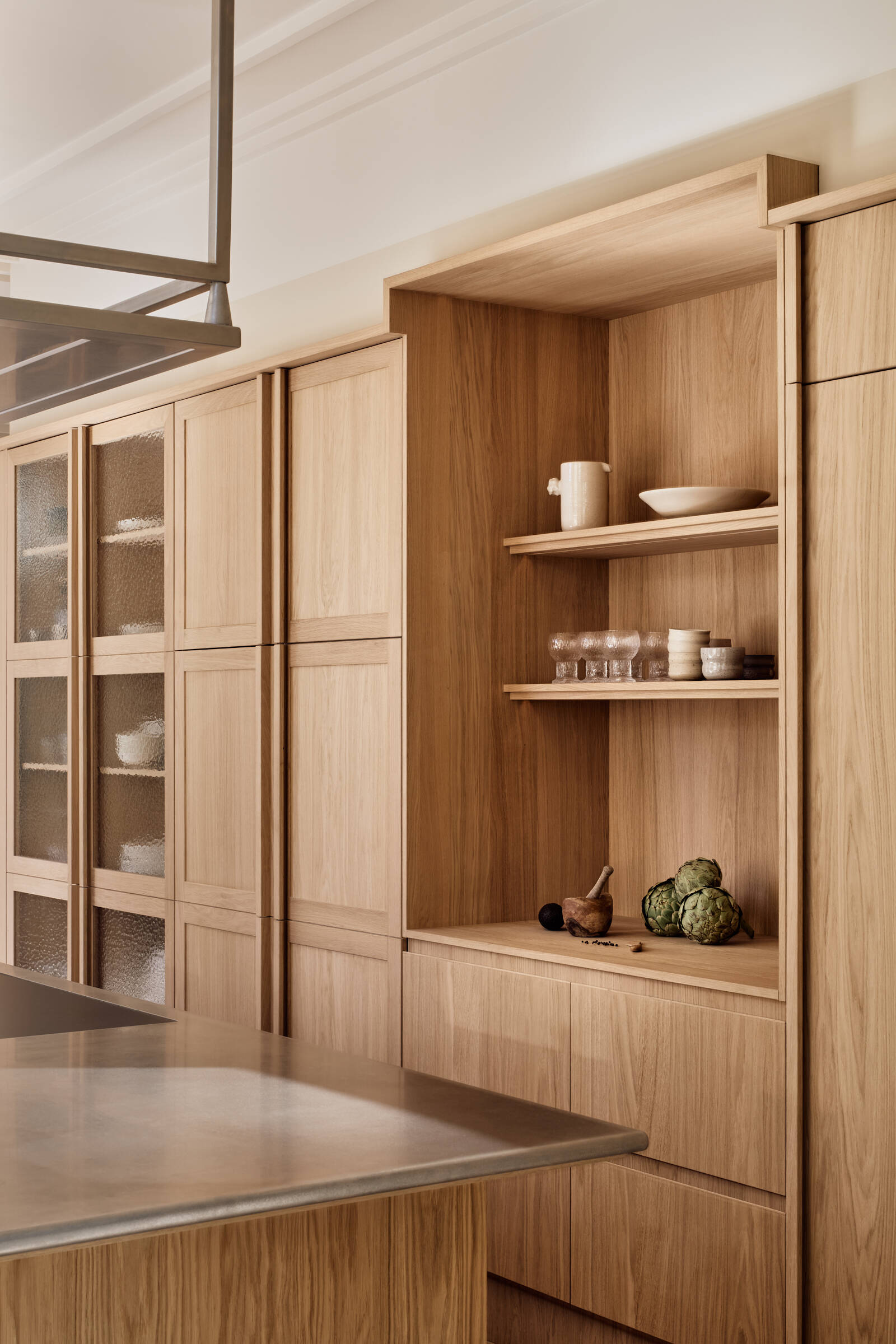 Warm wood cabinetry, textured glass, and stainless steel surfaces give this kitchen a perfect mix of comfort and modern edge.
