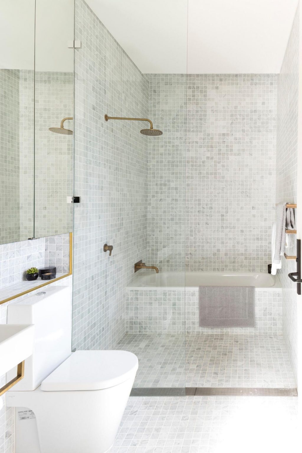 This modern bathroom has smaller grey square tiles, keeping the palette restrained while maintaining the industrial reference through texture and tone.