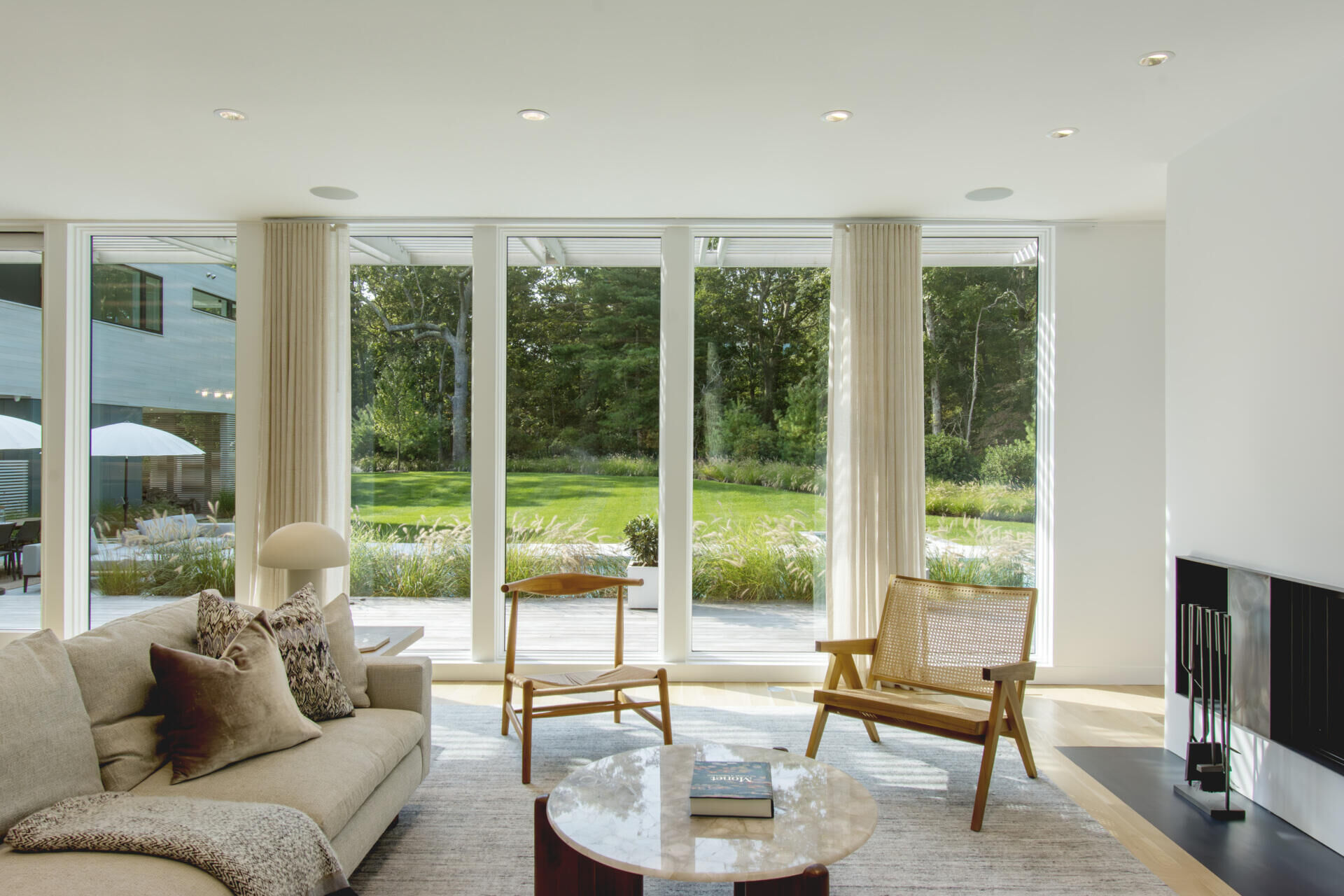 Floor-to-ceiling windows turn the surrounding woods into the focal point of this warm and modern living room.
