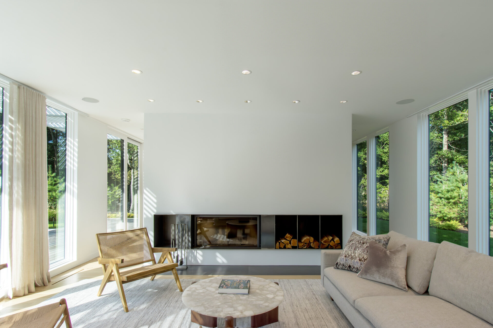 Floor-to-ceiling windows turn the surrounding woods into the focal point of this warm and modern living room.