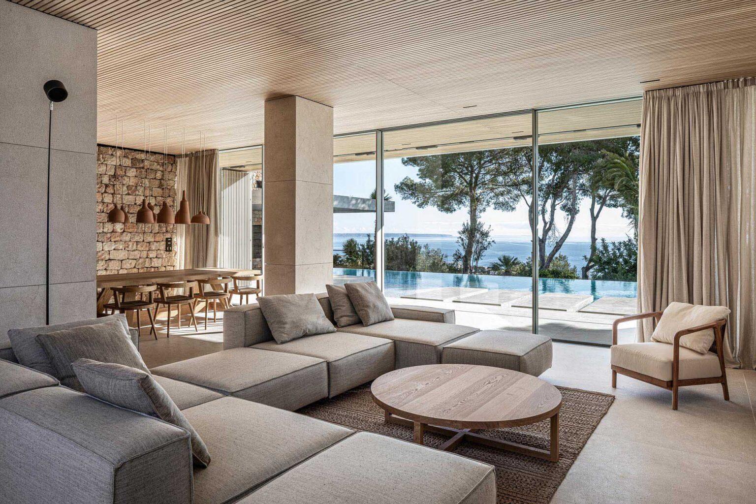 In the open-plan living and dining area, natural textures soften the modern architecture. Above the dining table, a cluster of handmade ceramic pendant lights creates a sculptural centerpiece while adding warmth to the room.