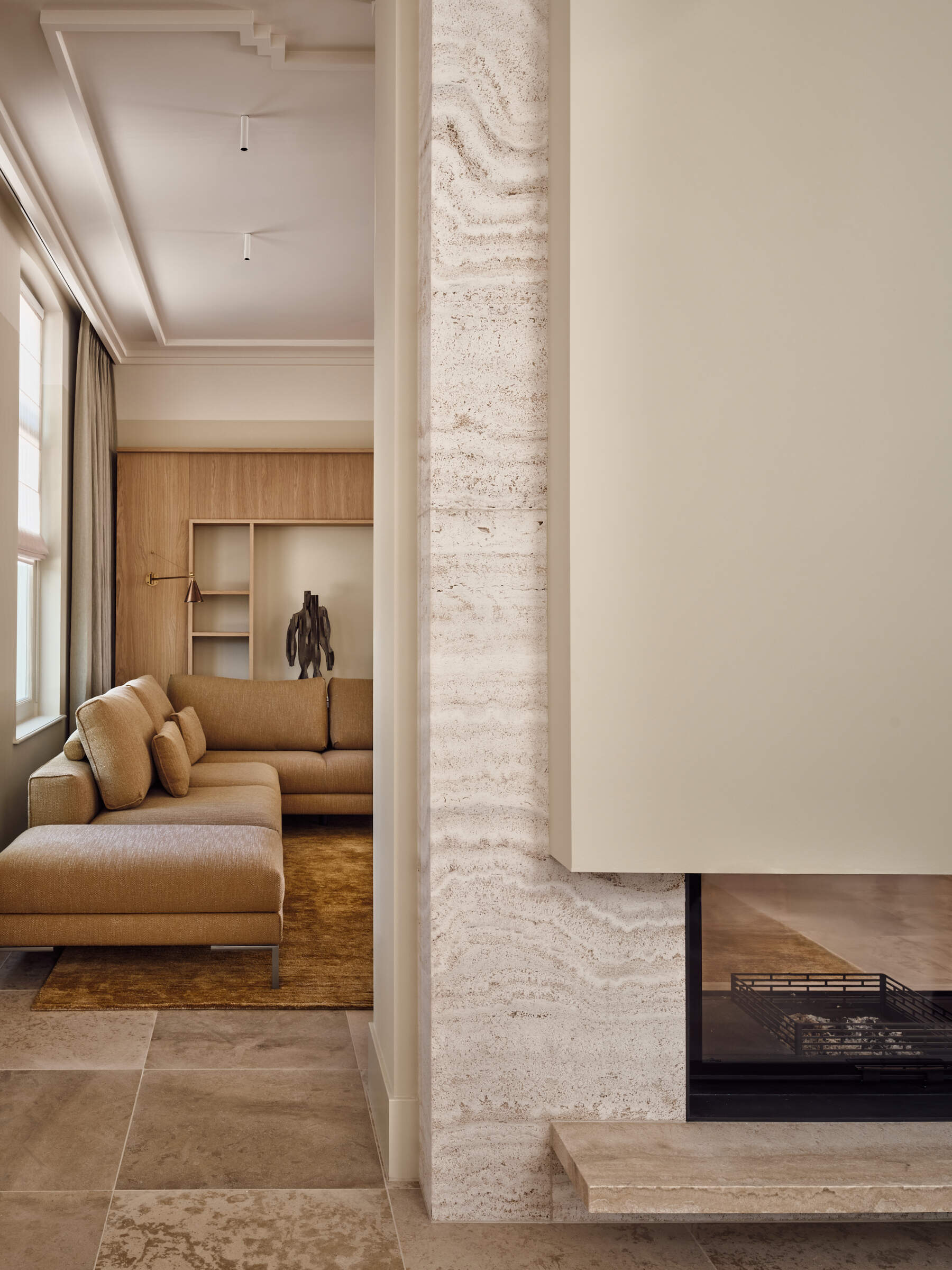 Warm walnut, textured glass, fireplaces, and custom seating make this riverside living room feel inviting, layered, and full of atmosphere.