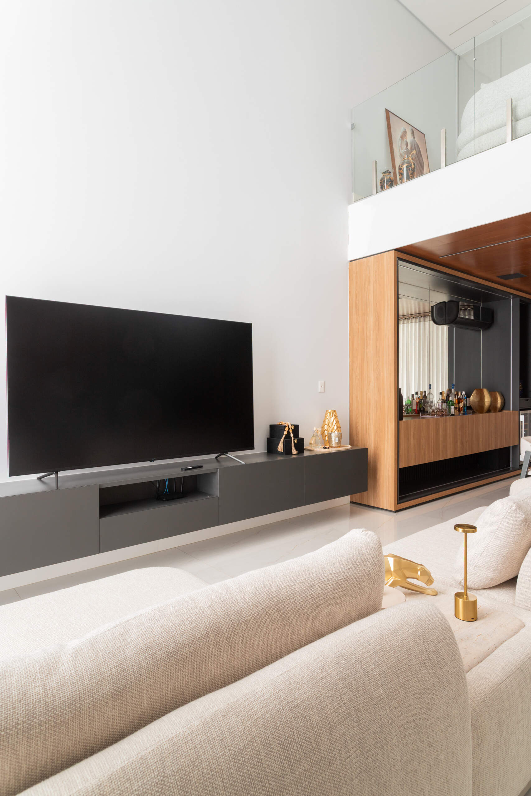 A dramatic double-height living room in Casa R|L combines exposed concrete, warm wood finishes, and sculptural structural elements in this contemporary Brazilian home.