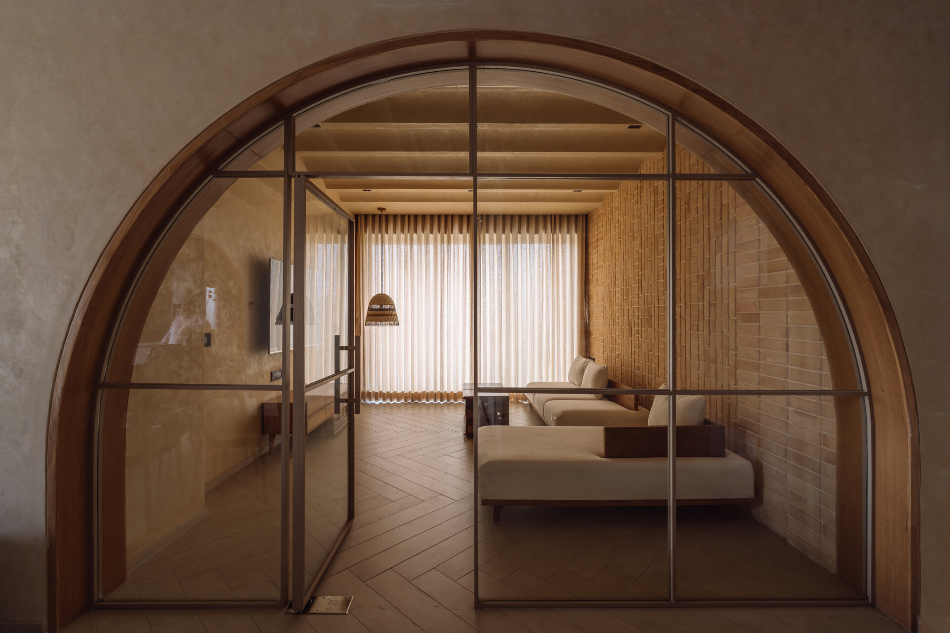 Exposed brick walls and sculptural arches give this Ahmedabad living room a warm minimalist atmosphere filled with texture, light, and soft architectural forms.