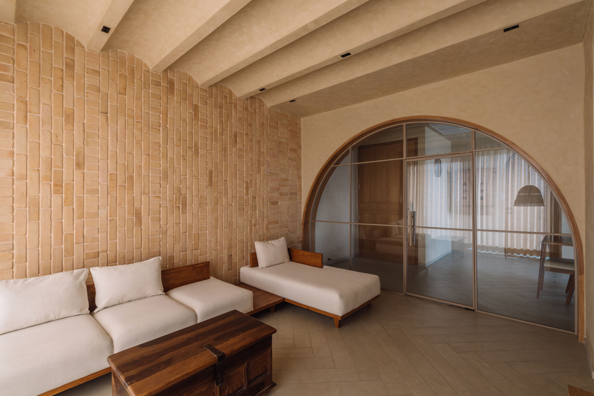 Exposed brick walls and sculptural arches give this Ahmedabad living room a warm minimalist atmosphere filled with texture, light, and soft architectural forms.