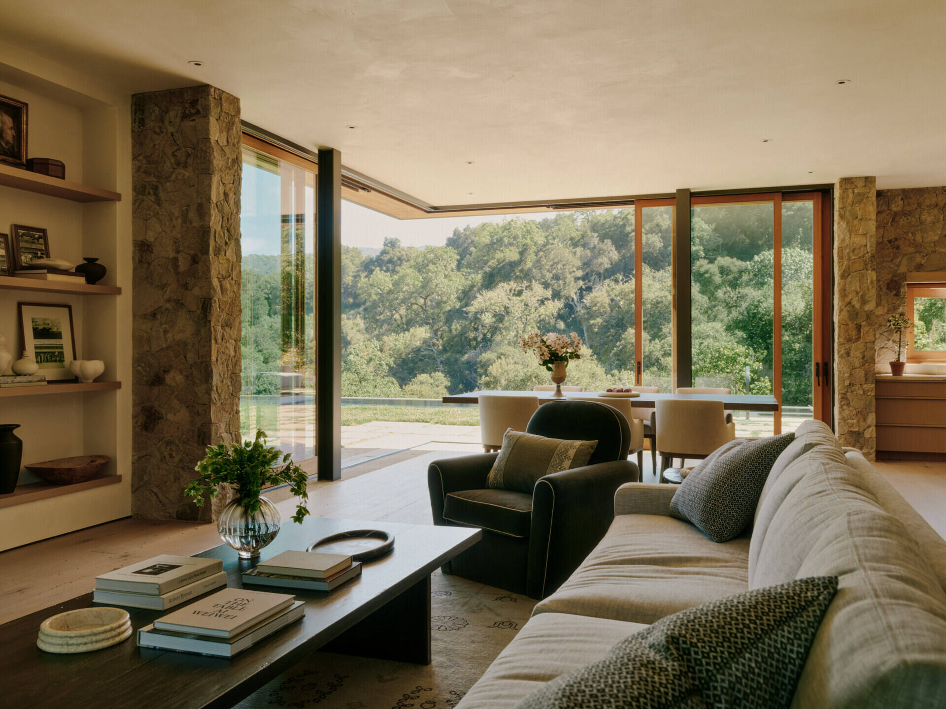 Warm stone, natural wood, and panoramic valley views define the open living and dining spaces inside this modern California villa.