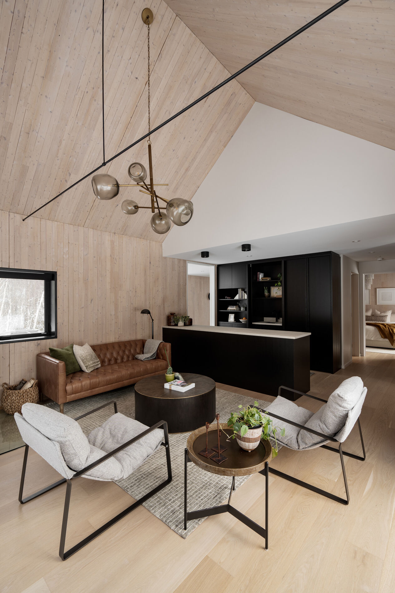 A modern living room with a fireplace in the corner and large windows that look out onto the landscape.