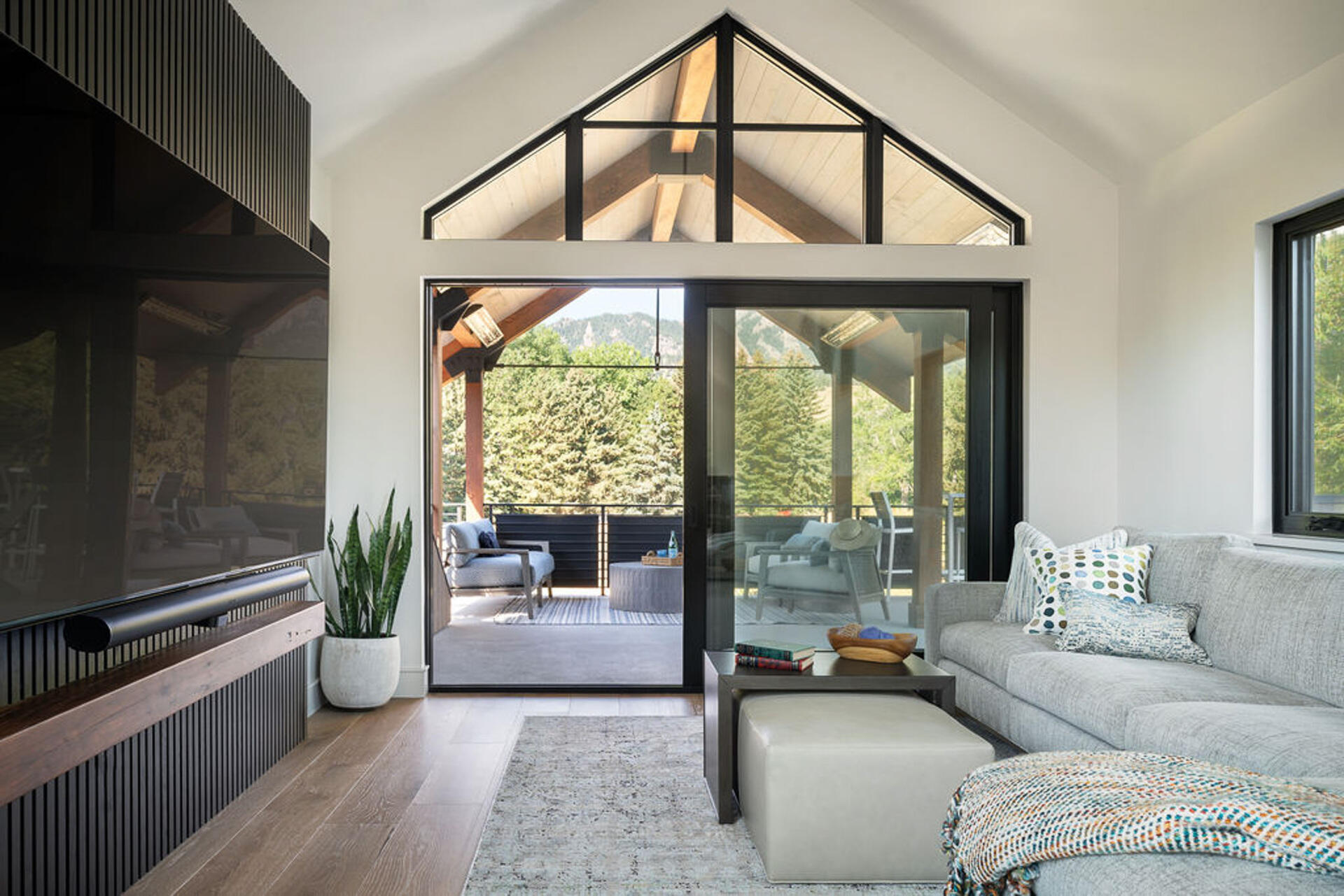 This sunlit upper-level living room uses interior glazing and mountain views to create a bright modern retreat.