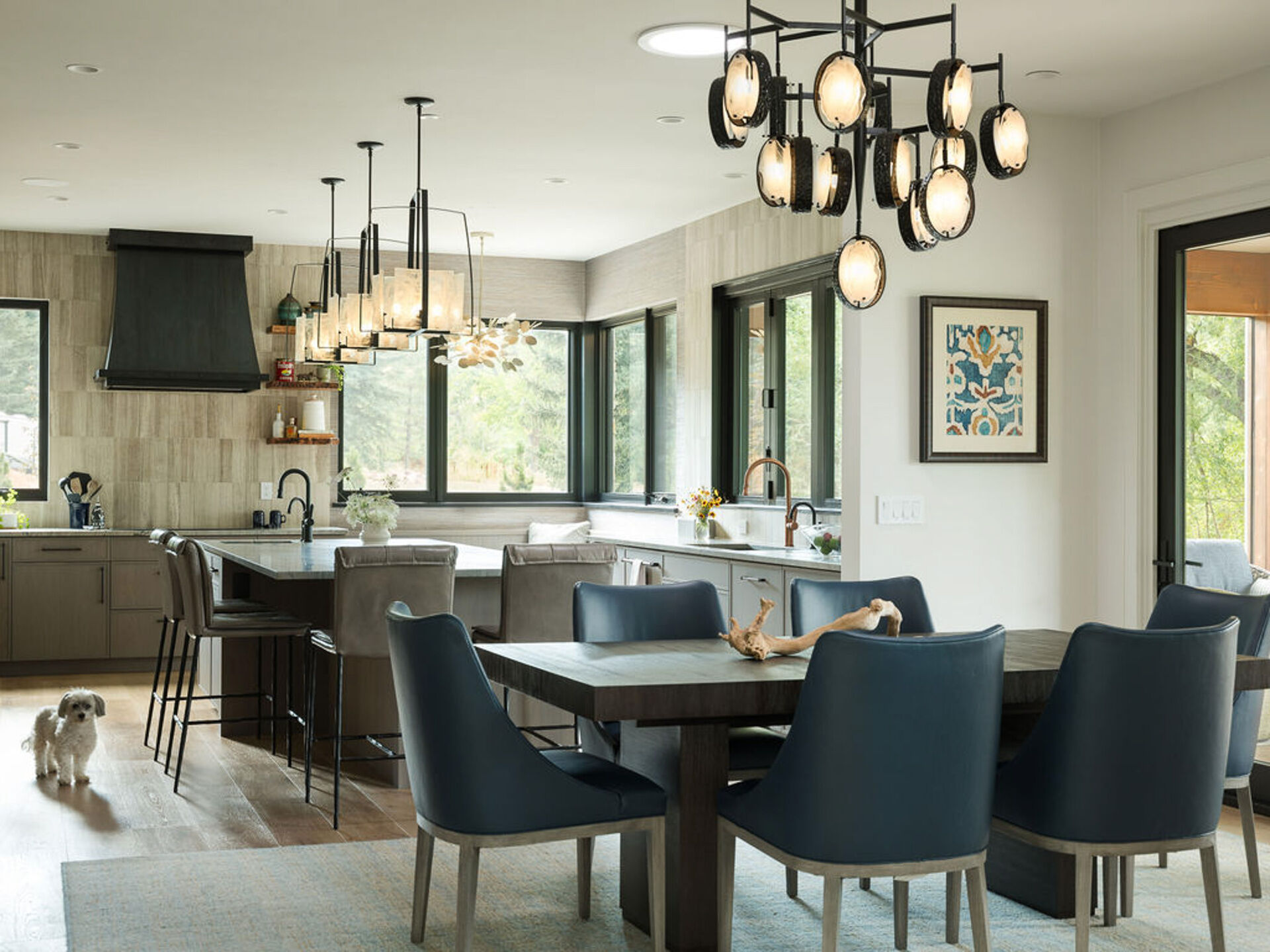 Dark wood furniture, sculptural lighting, and large black-framed windows shape this warm modern dining area in Boulder, Colorado.