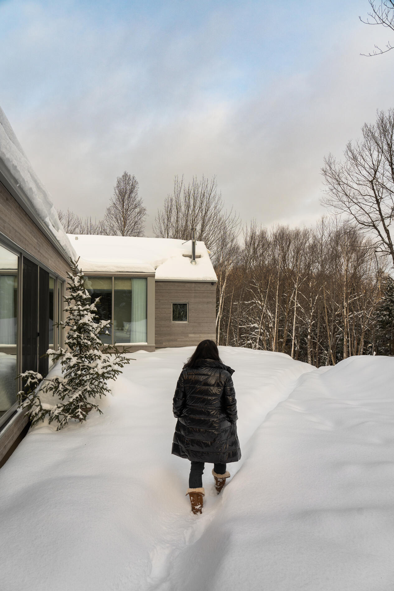 A Quebec mountain house built with cross-laminated timber, featuring gabled volumes and a pinwheel layout that blends into the surrounding landscape.