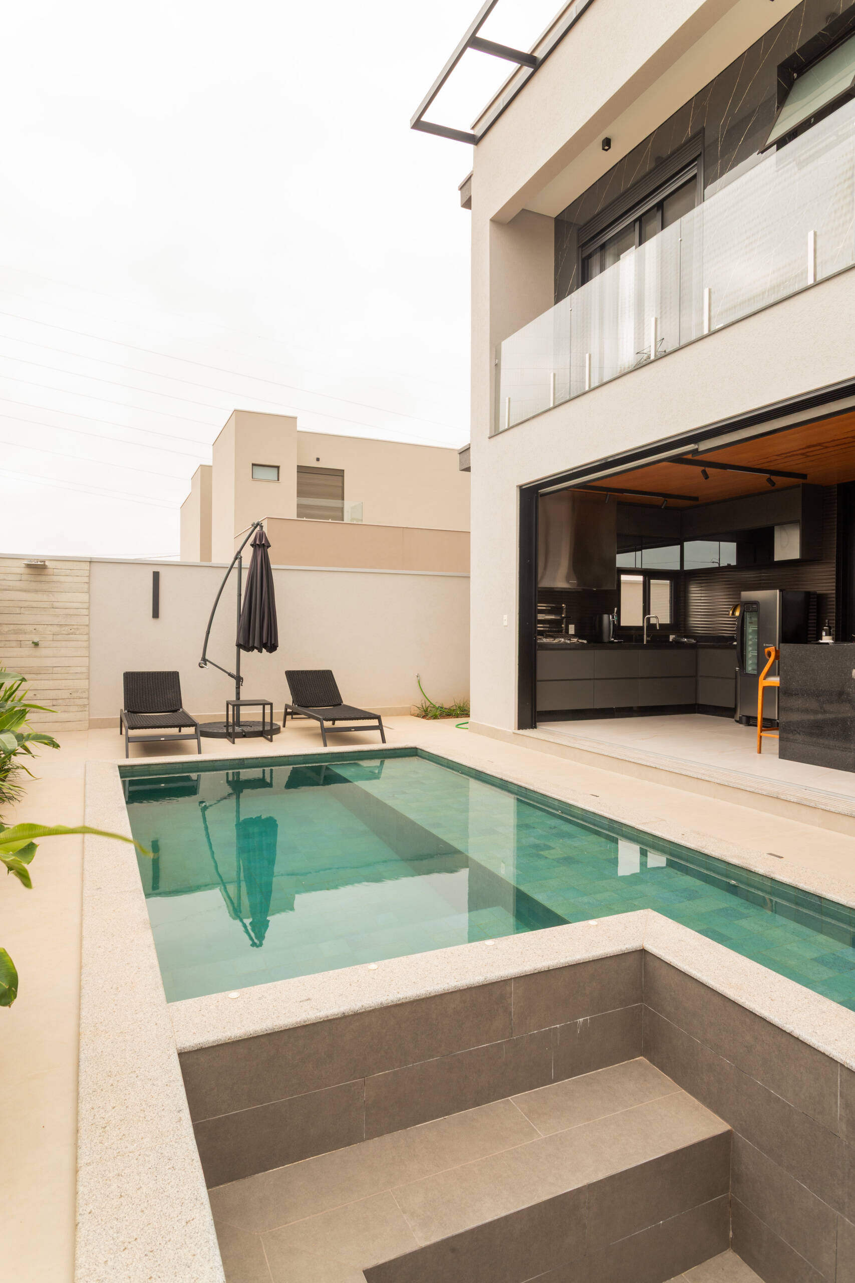 This contemporary pool area reflects the sculptural geometry of Casa R|L, featuring clean lines, concrete textures, and modern outdoor living in Brazil.