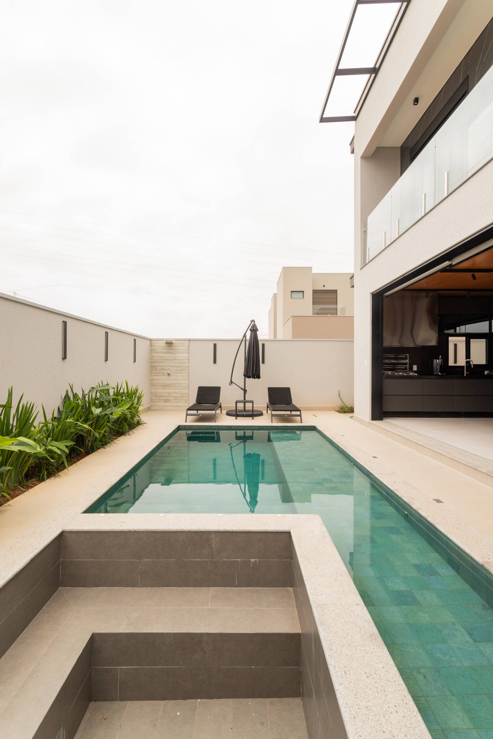This contemporary pool area reflects the sculptural geometry of Casa R|L, featuring clean lines, concrete textures, and modern outdoor living in Brazil.