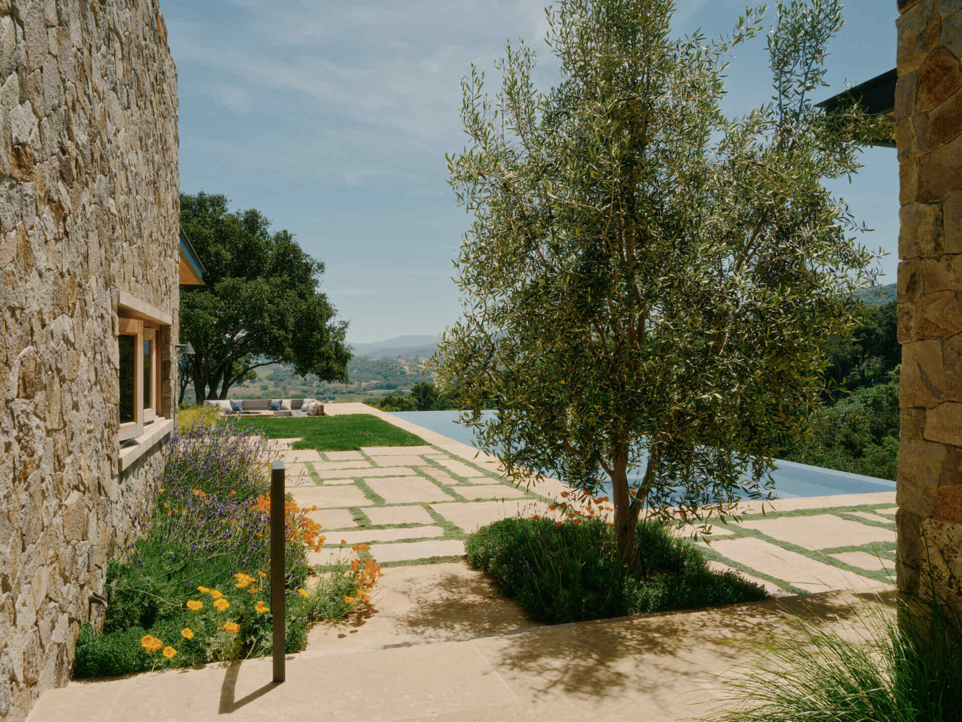 This ridge-top pool area combines stone walls, open views, and an outdoor shower for a relaxed California outdoor living experience.