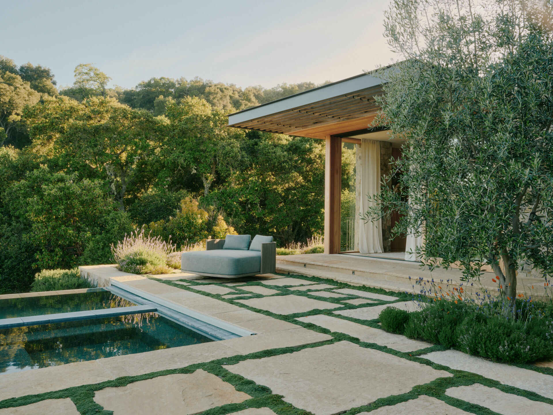 This ridge-top pool area combines stone walls, open views, and an outdoor shower for a relaxed California outdoor living experience.