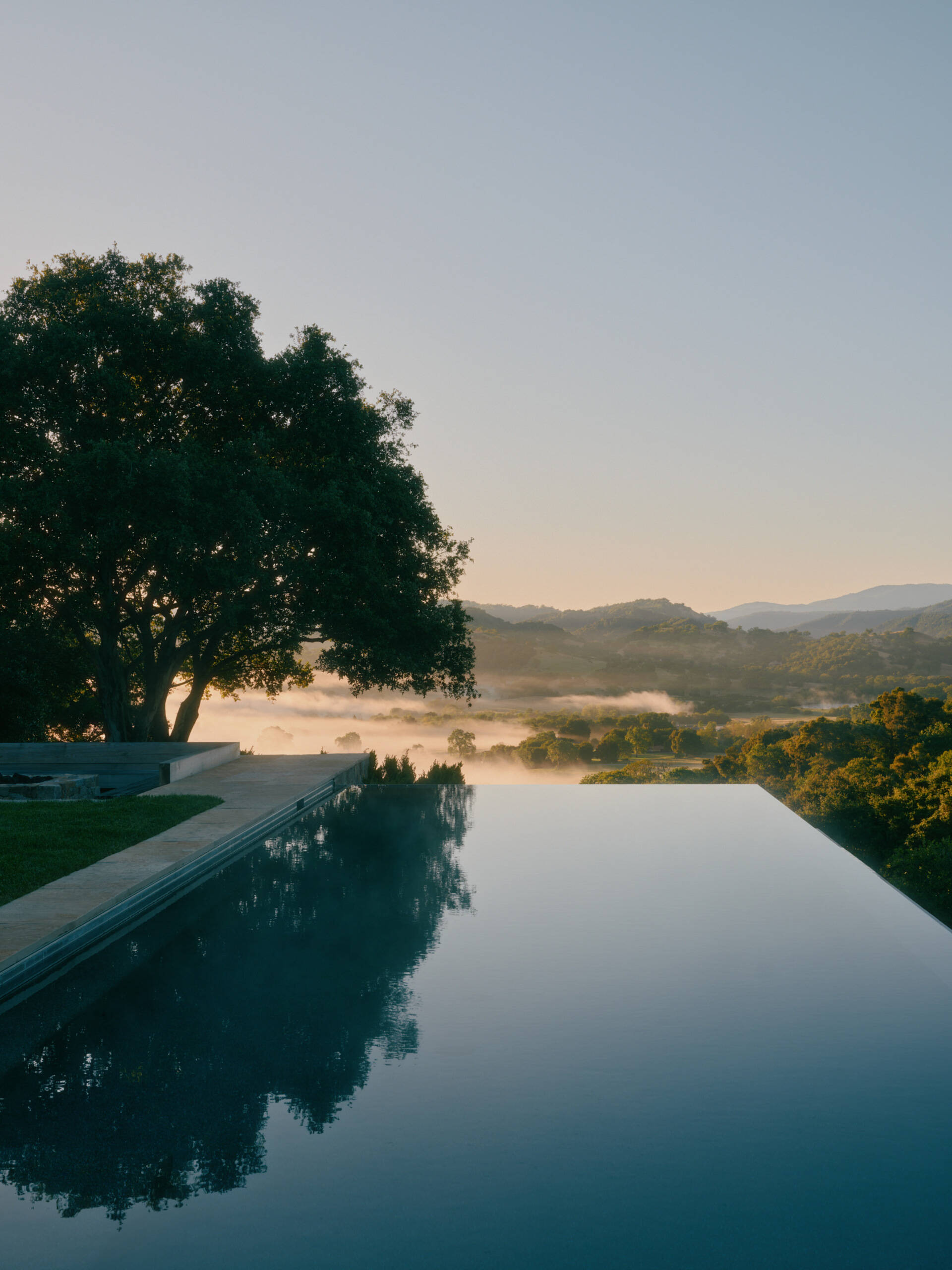 This ridge-top pool area combines stone walls, open views, and an outdoor shower for a relaxed California outdoor living experience.