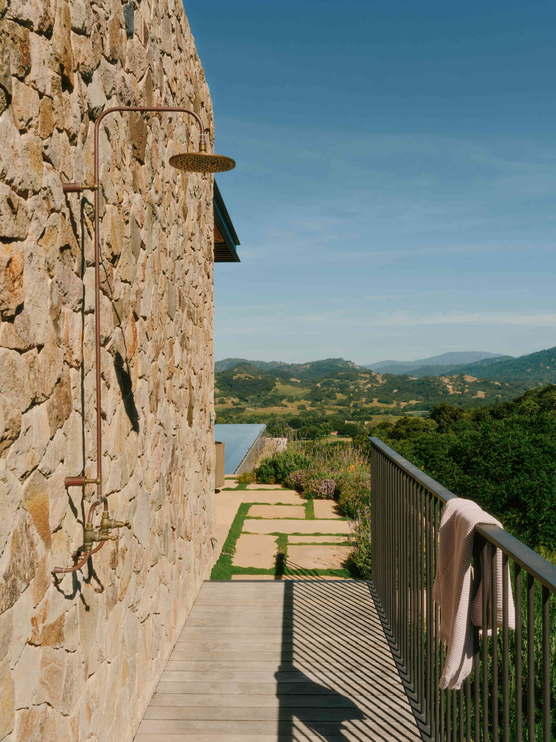 This ridge-top pool area combines stone walls, open views, and an outdoor shower for a relaxed California outdoor living experience.