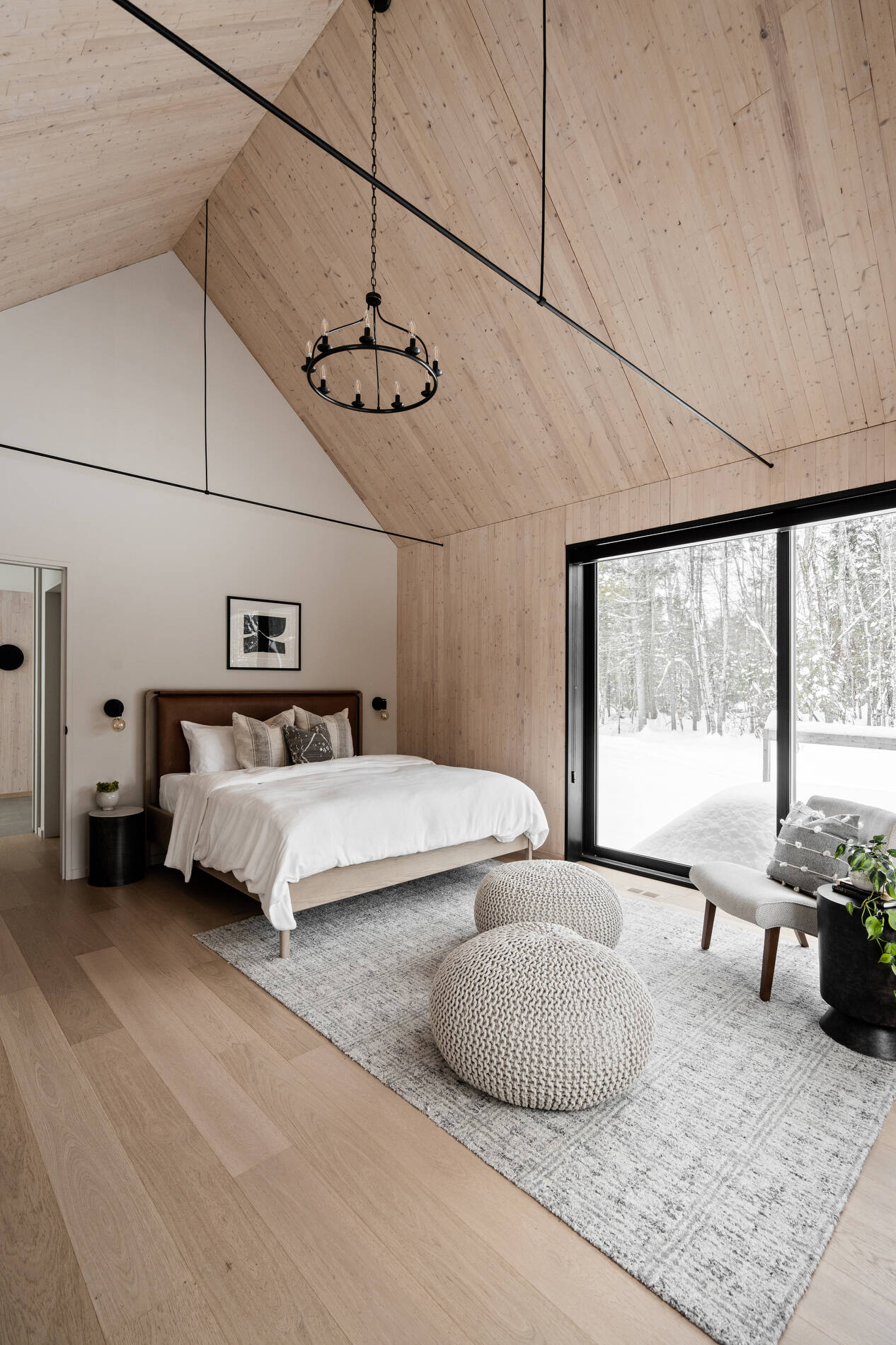 A private primary suite with timber interiors and large windows, offering a quiet connection to the surrounding landscape.