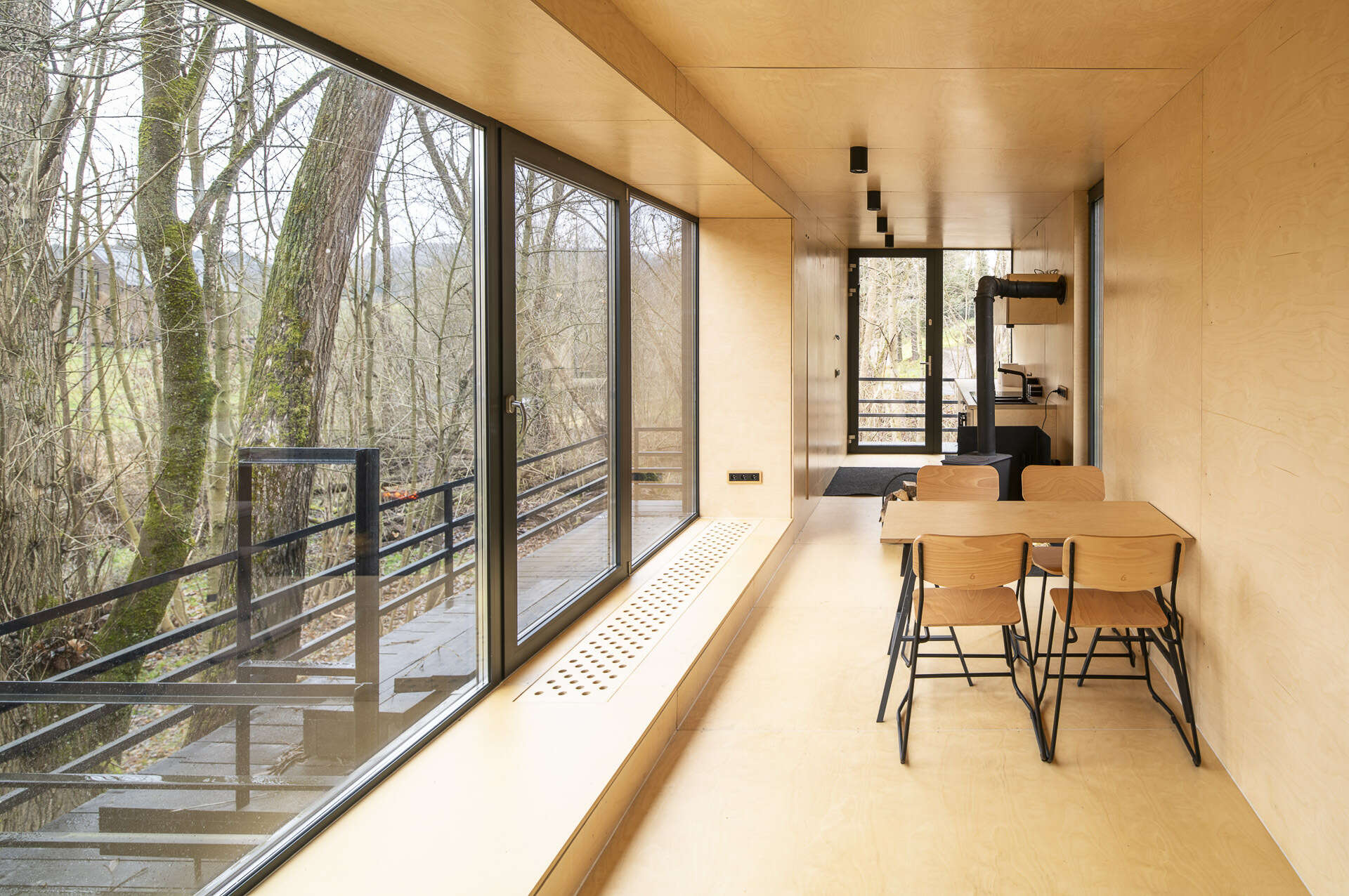 Inside Offroadhouse, warm plywood walls, hidden storage, a compact open-plan layout, and framed nature views create a calm minimalist interior inspired by Zen design.