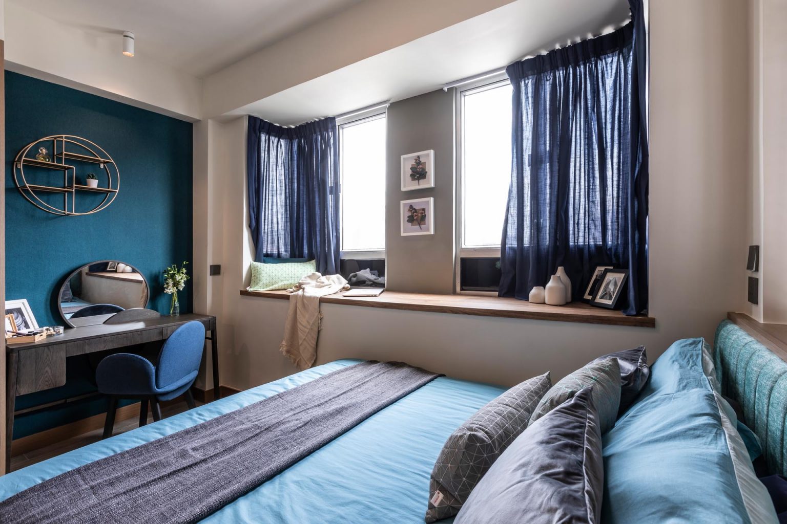 Blue textured wallpaper and a built-in window seat create a cozy workspace inside this small modern apartment in Hong Kong.