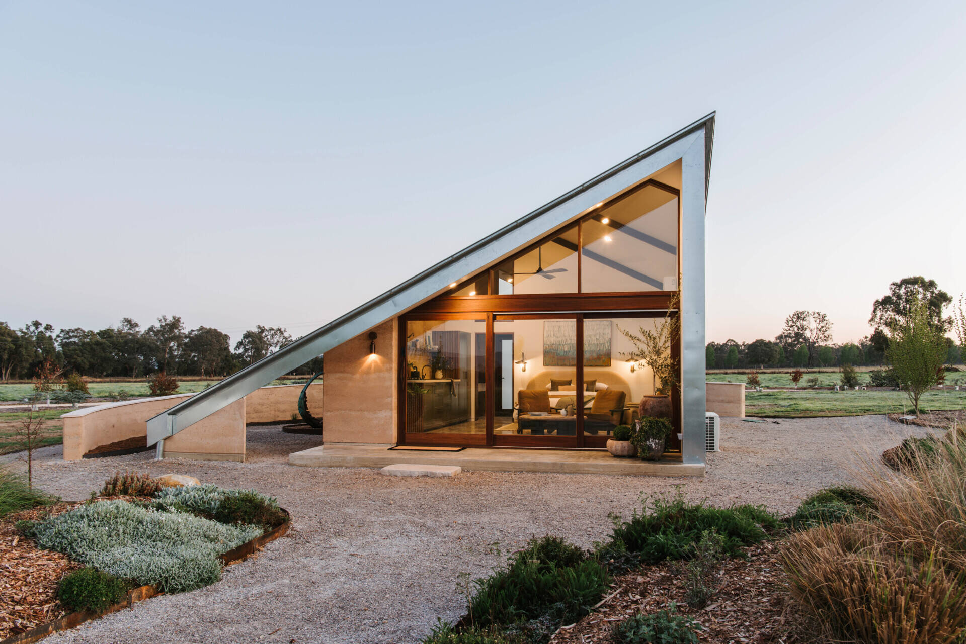 Compact off-grid cabins in Mudgee designed with rammed earth, timber, and a folded roof that reimagines camping through architecture.