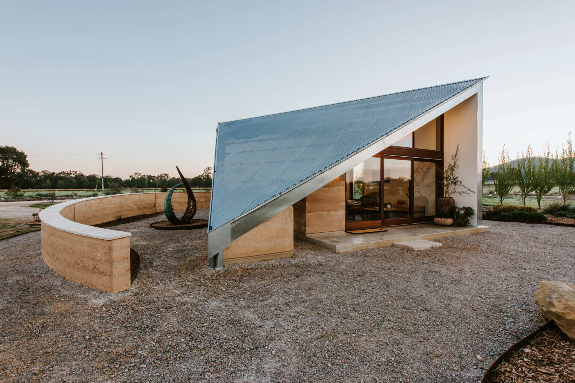Compact off-grid cabins in Mudgee designed with rammed earth, timber, and a folded roof that reimagines camping through architecture.