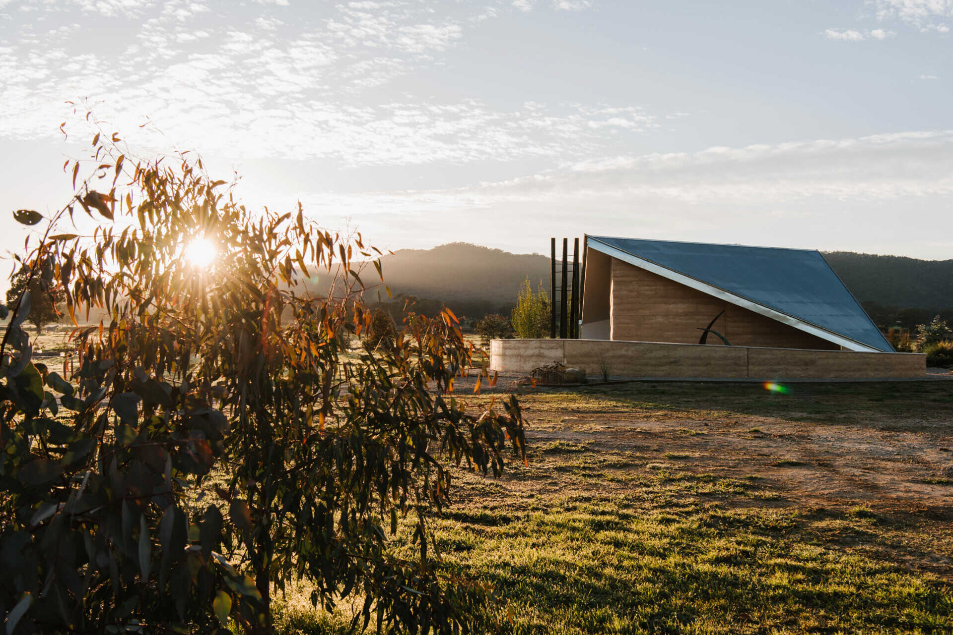 Compact off-grid cabins in Mudgee designed with rammed earth, timber, and a folded roof that reimagines camping through architecture.