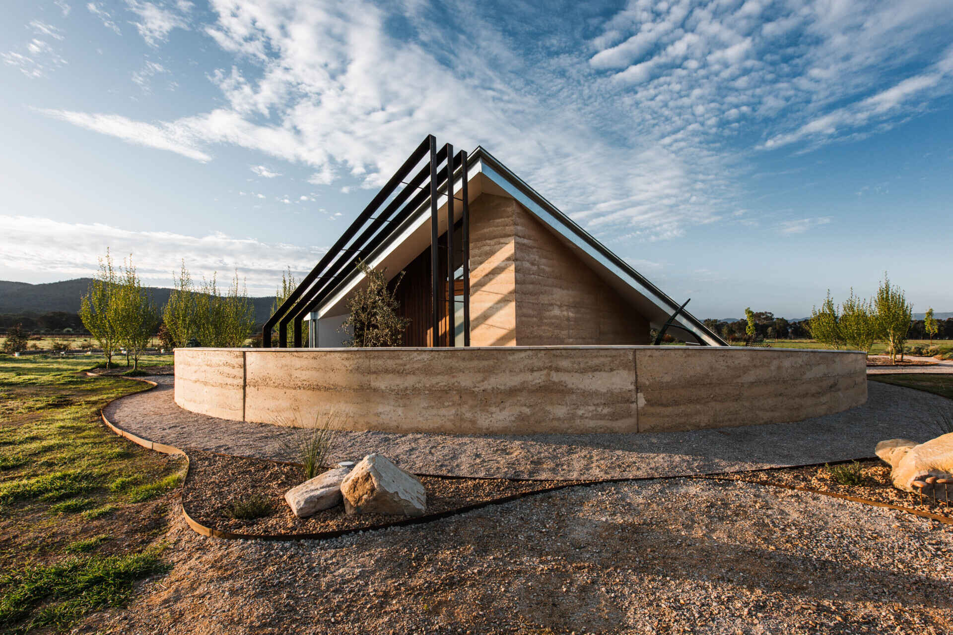Compact off-grid cabins in Mudgee designed with rammed earth, timber, and a folded roof that reimagines camping through architecture.