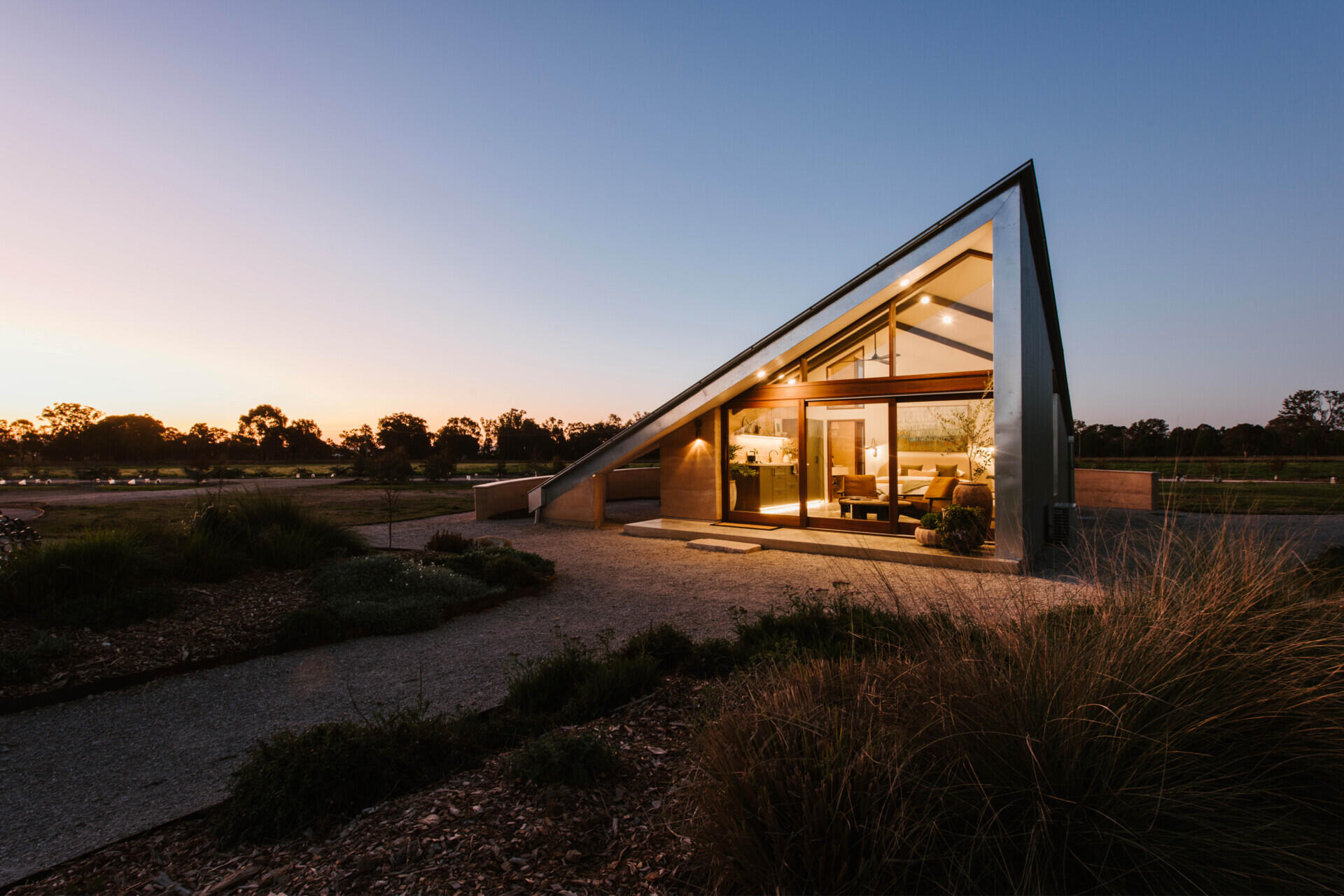 Compact off-grid cabins in Mudgee designed with rammed earth, timber, and a folded roof that reimagines camping through architecture.