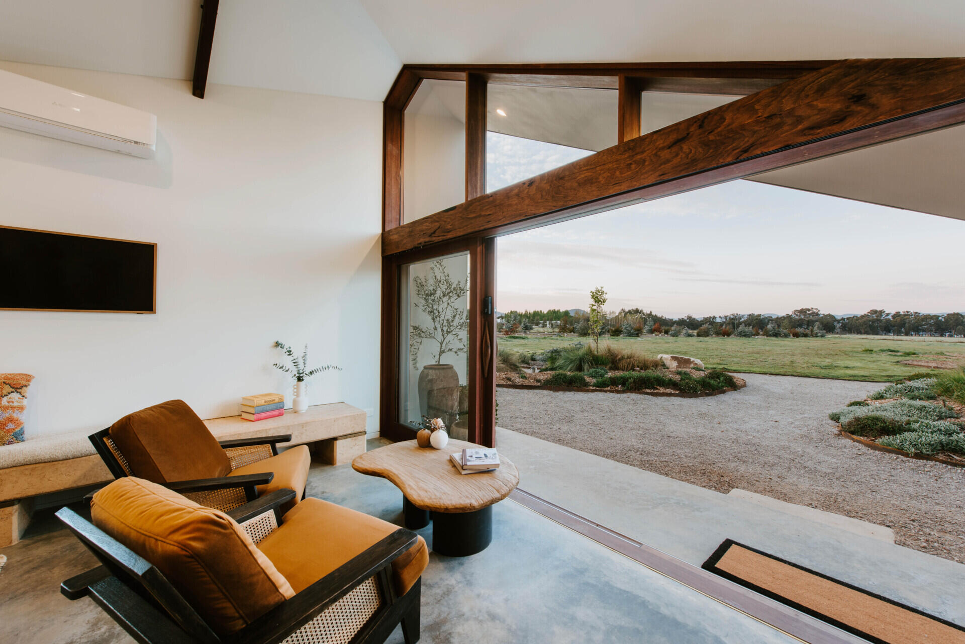 The interiors of a compact off-grid cabin designed with rammed earth, timber, and a folded roof that reimagines camping through architecture.