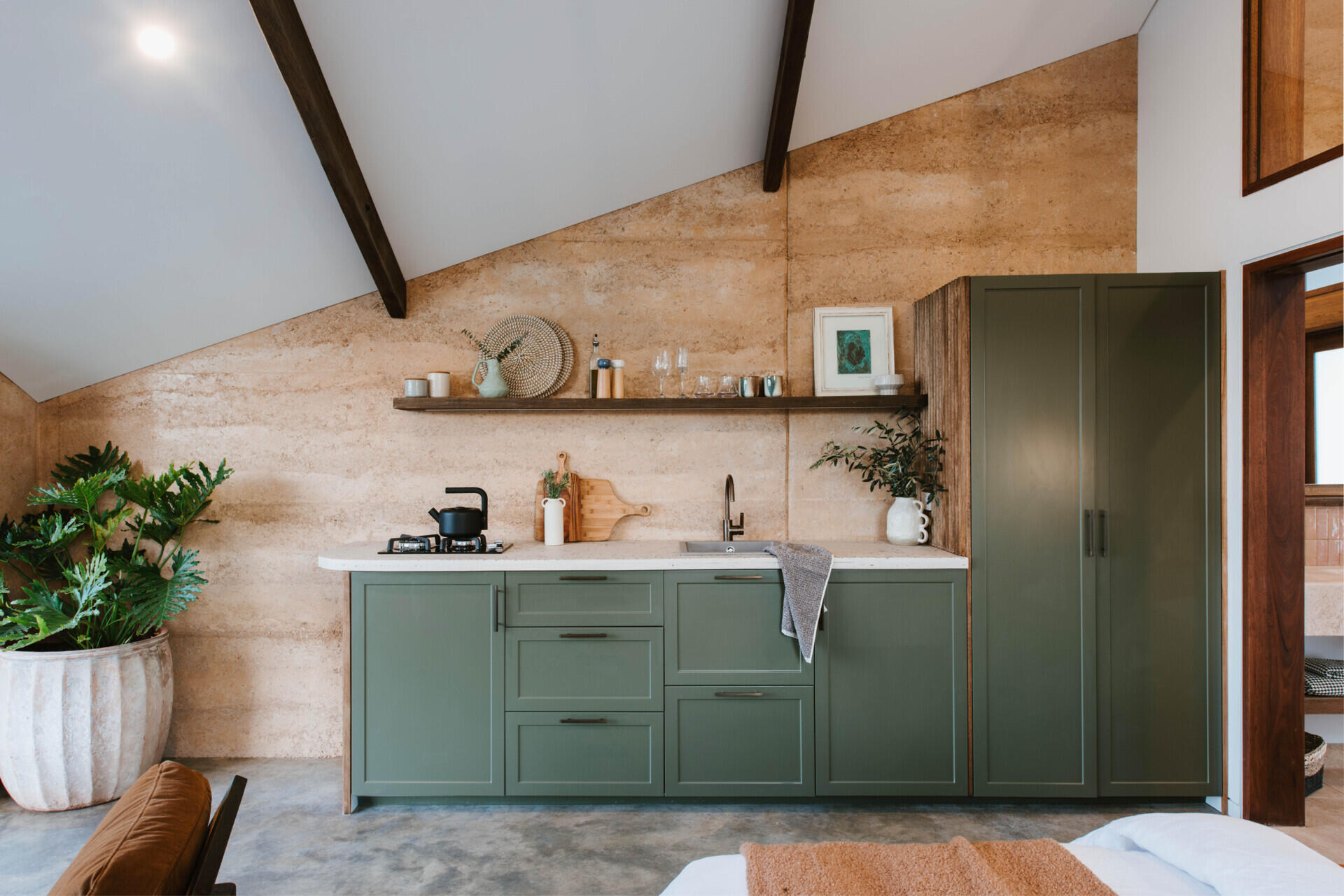 The interiors of a compact off-grid cabin designed with rammed earth, timber, and a folded roof that reimagines camping through architecture.