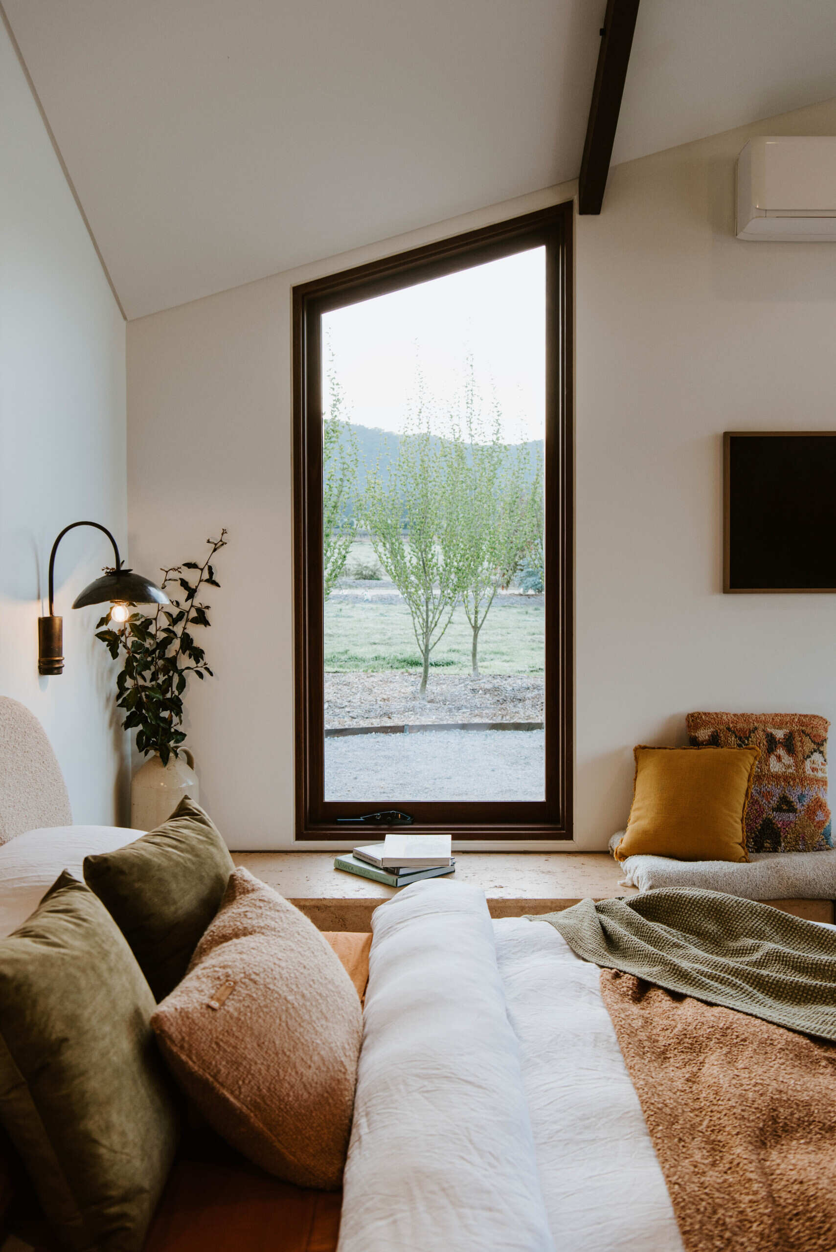 The interiors of a compact off-grid cabin designed with rammed earth, timber, and a folded roof that reimagines camping through architecture.