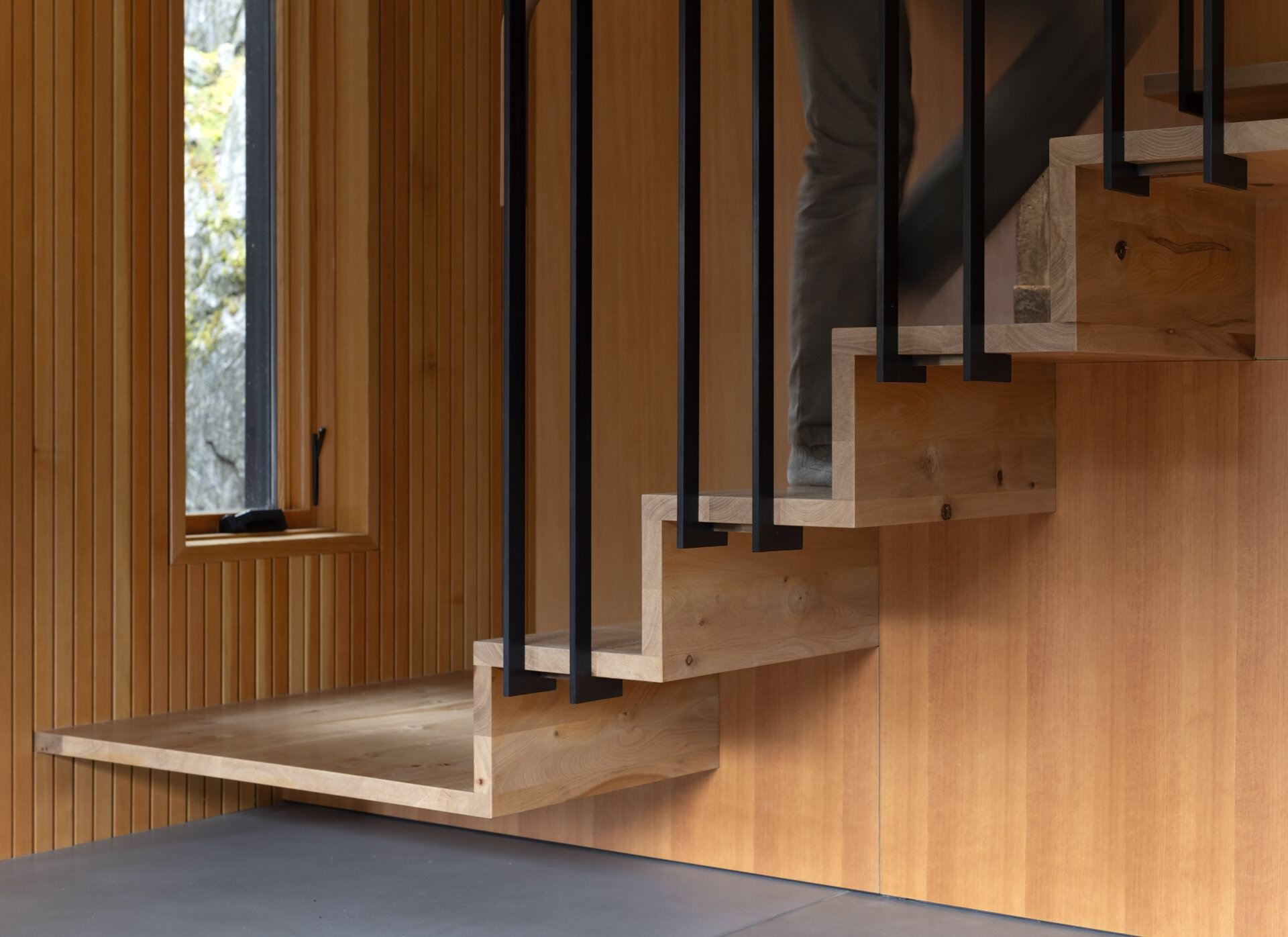 Floating madrone stairs, built-in shelving, and a ceramic fireplace turn this living room into a functional work of art.