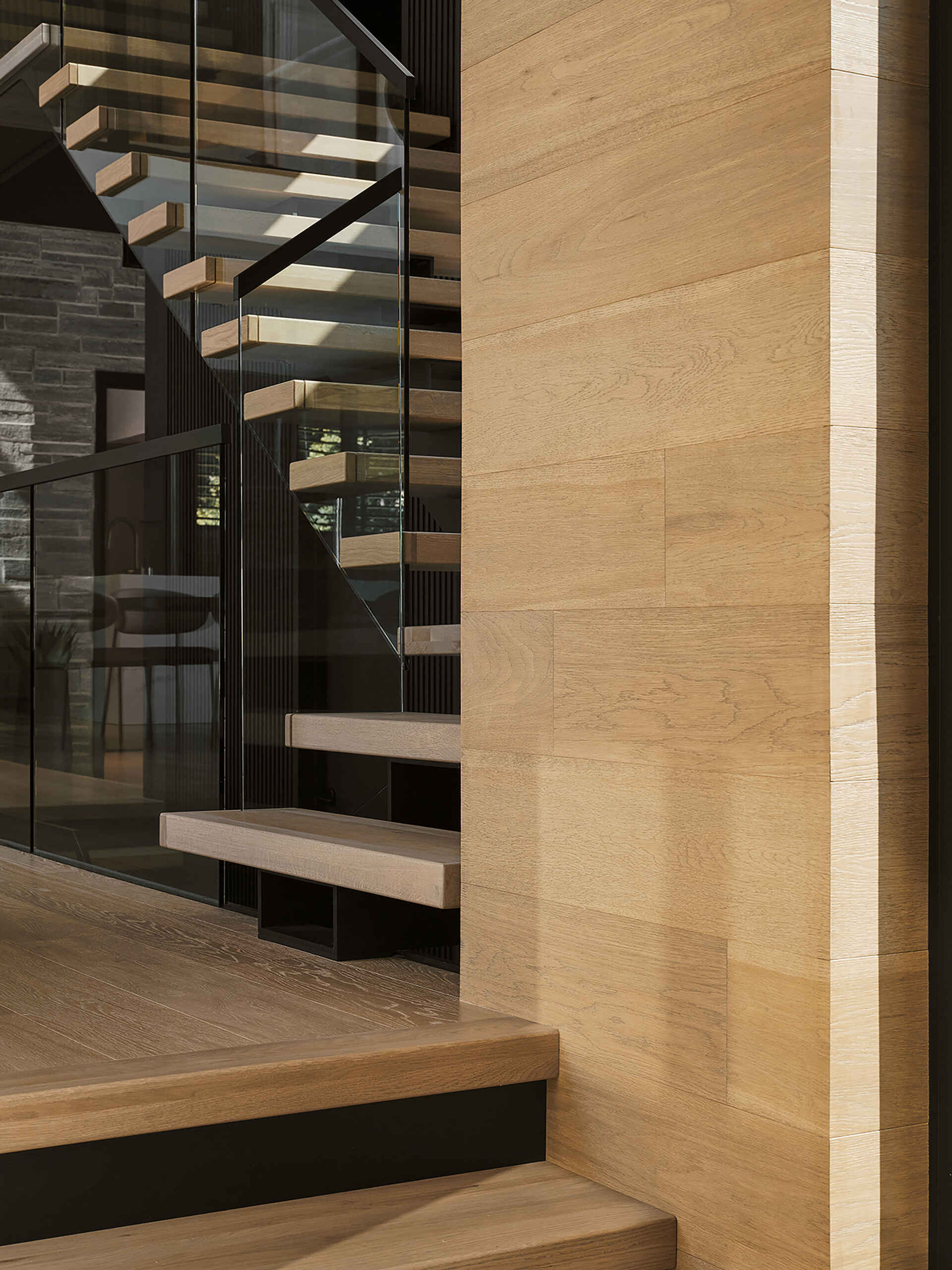 This floating staircase with glass railings creates a light-filled architectural statement connecting all three levels of the home.