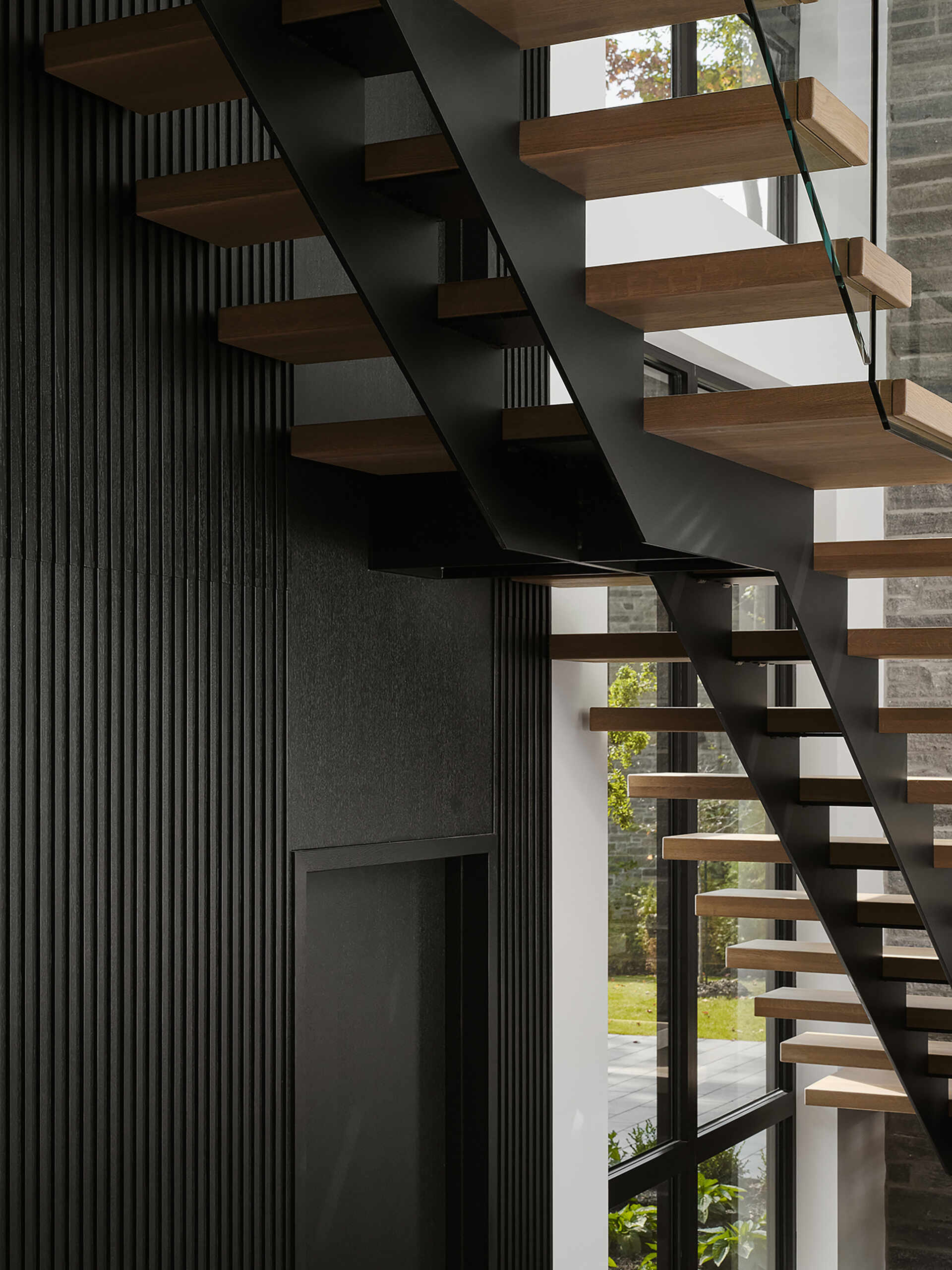 This floating staircase with glass railings creates a light-filled architectural statement connecting all three levels of the home.