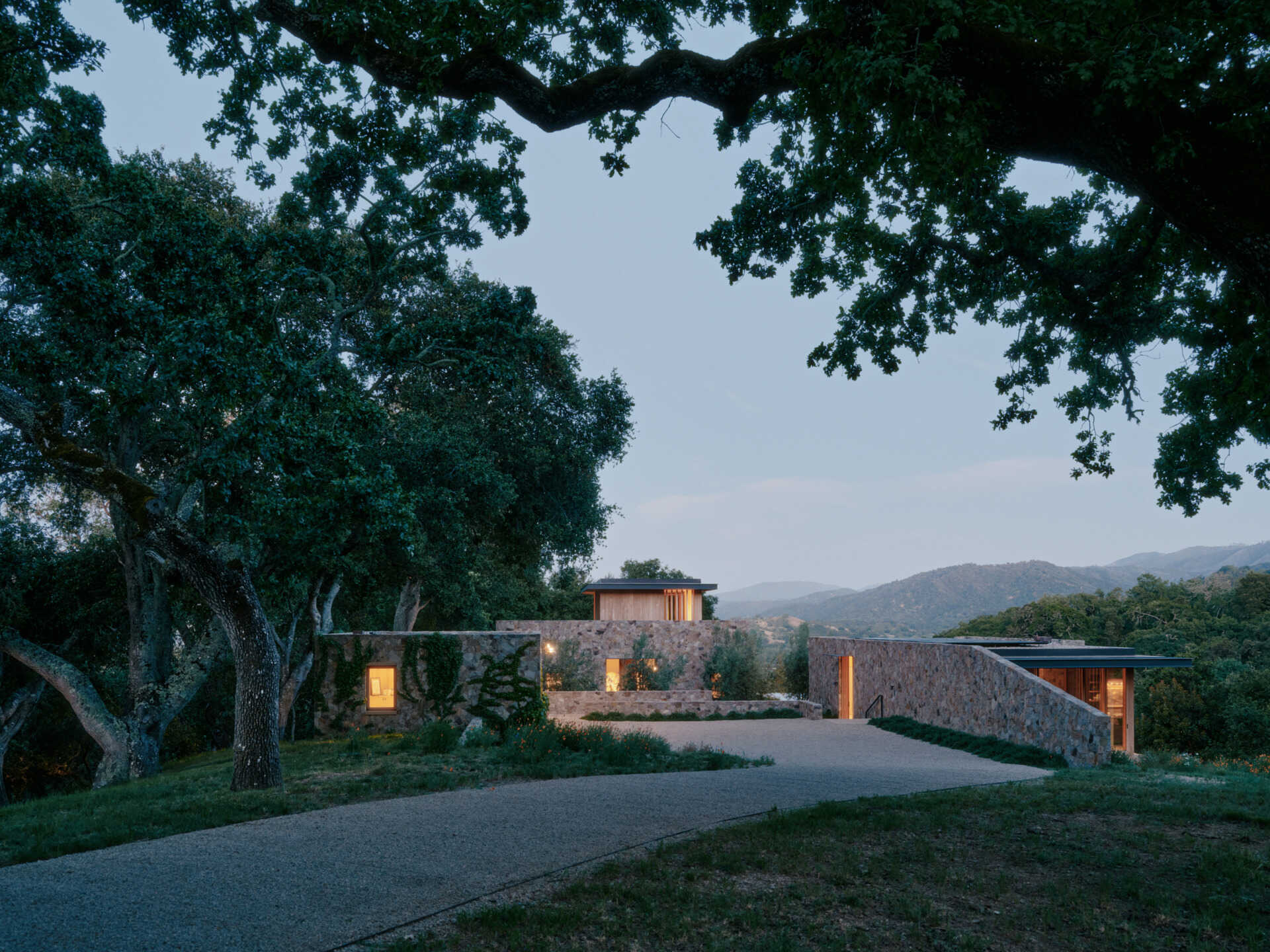 Four separate stone pavilions step across the California hillside, creating a modern villa layout inspired by Tuscan villages and open-air living.
