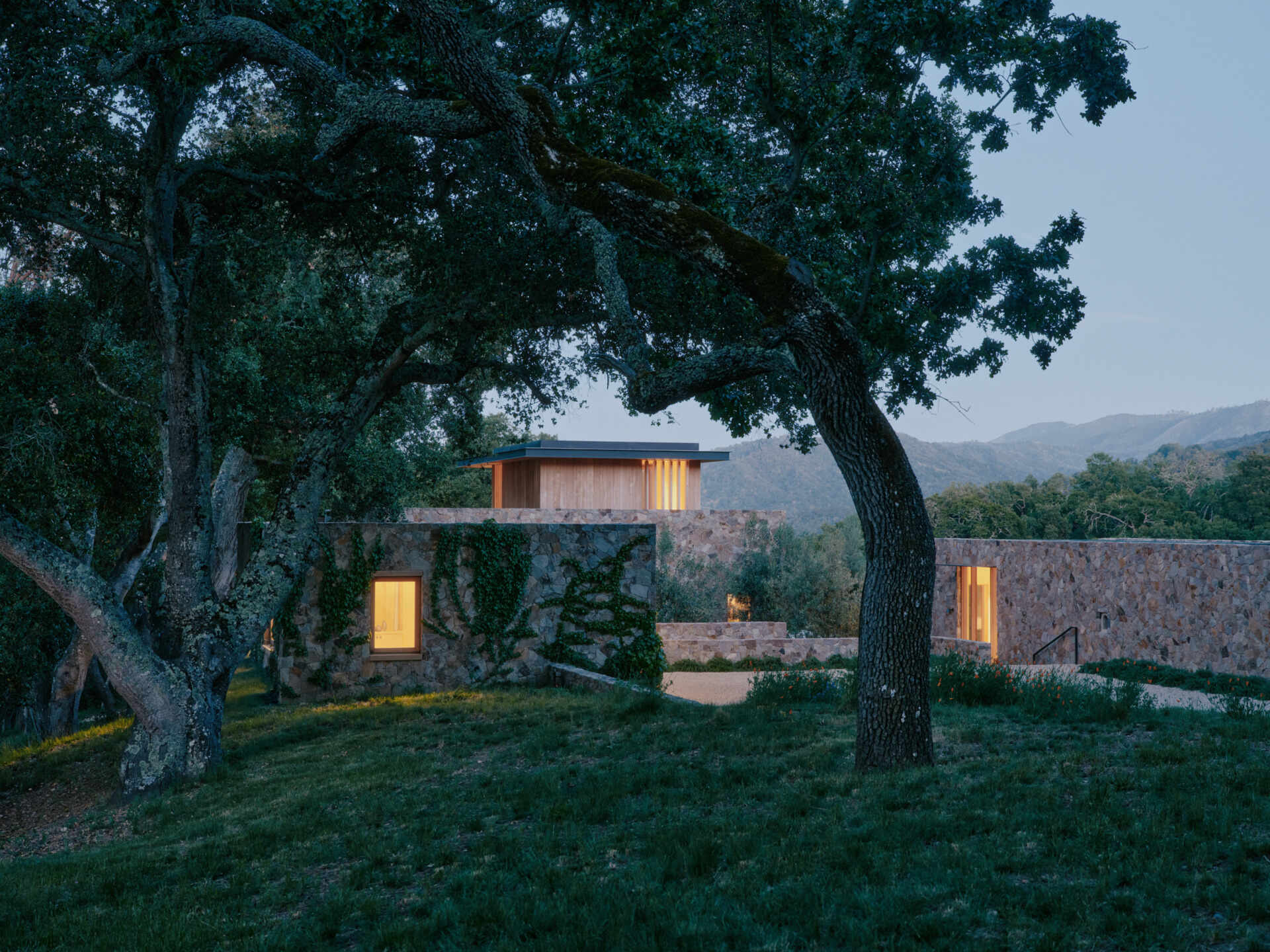 Four separate stone pavilions step across the California hillside, creating a modern villa layout inspired by Tuscan villages and open-air living.