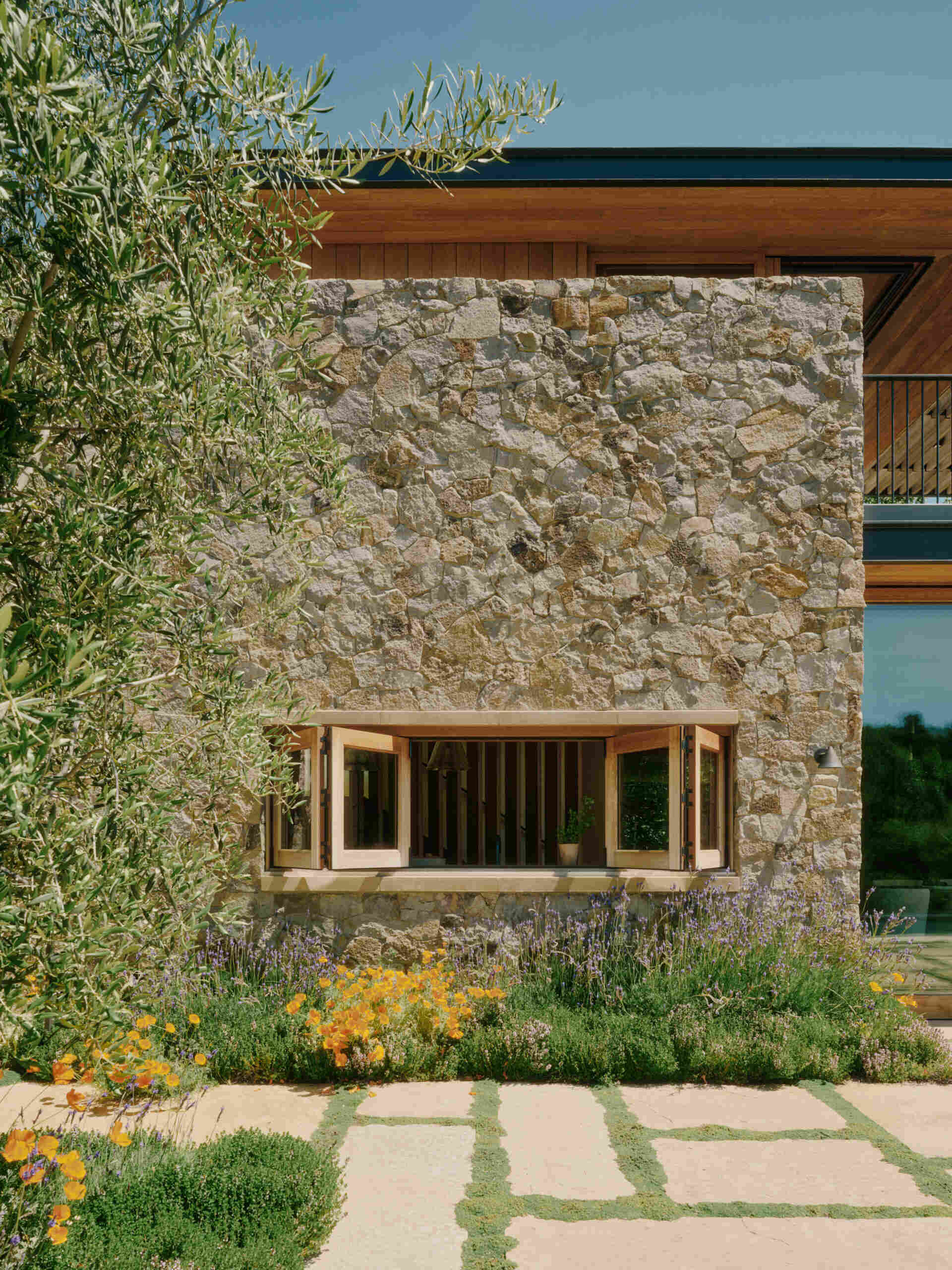 Four separate stone pavilions step across the California hillside, creating a modern villa layout inspired by Tuscan villages and open-air living.