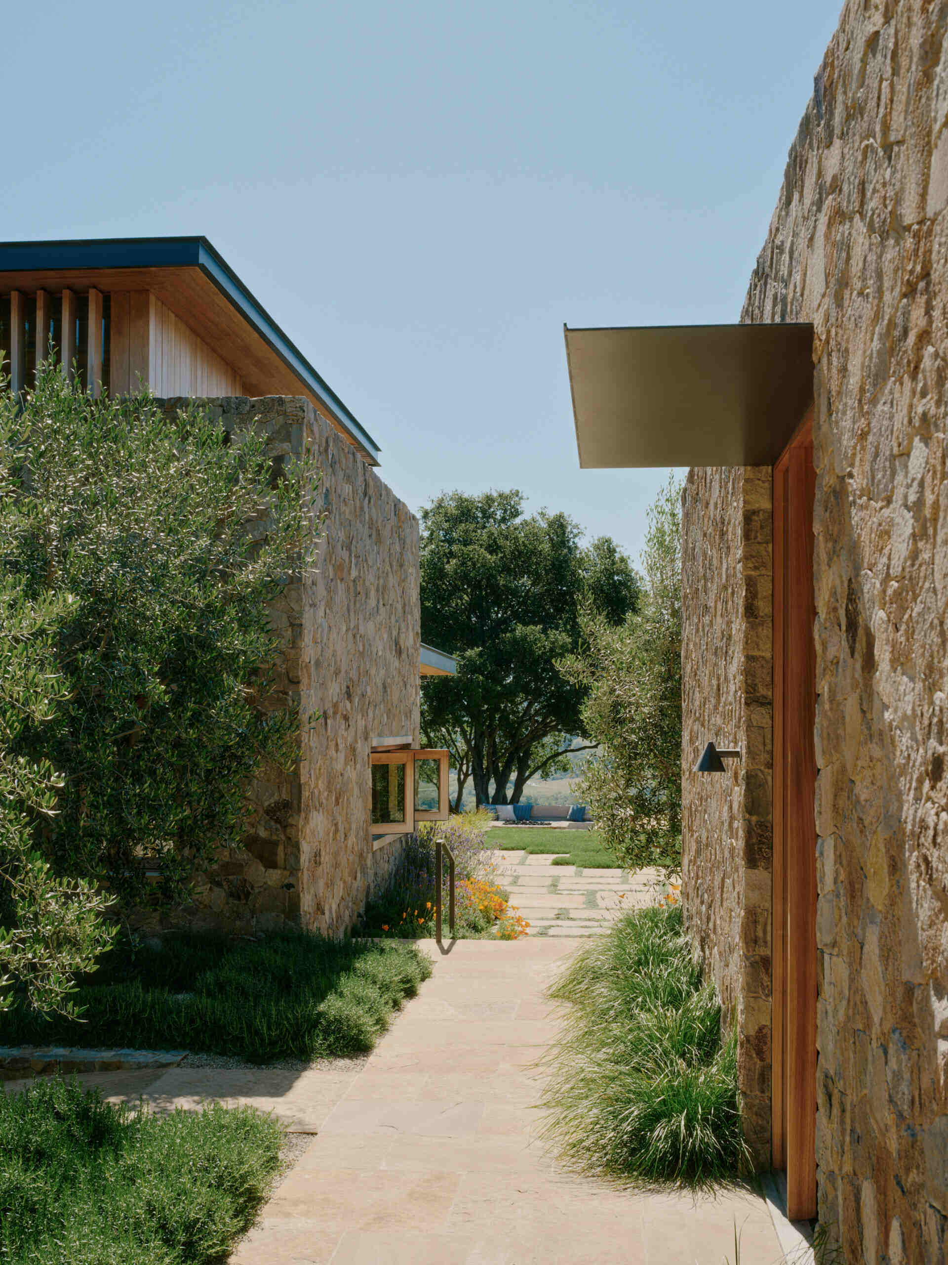 Stone pathways and drought-tolerant landscaping connect the pavilions of this California villa through gardens, courtyards, and hillside views.