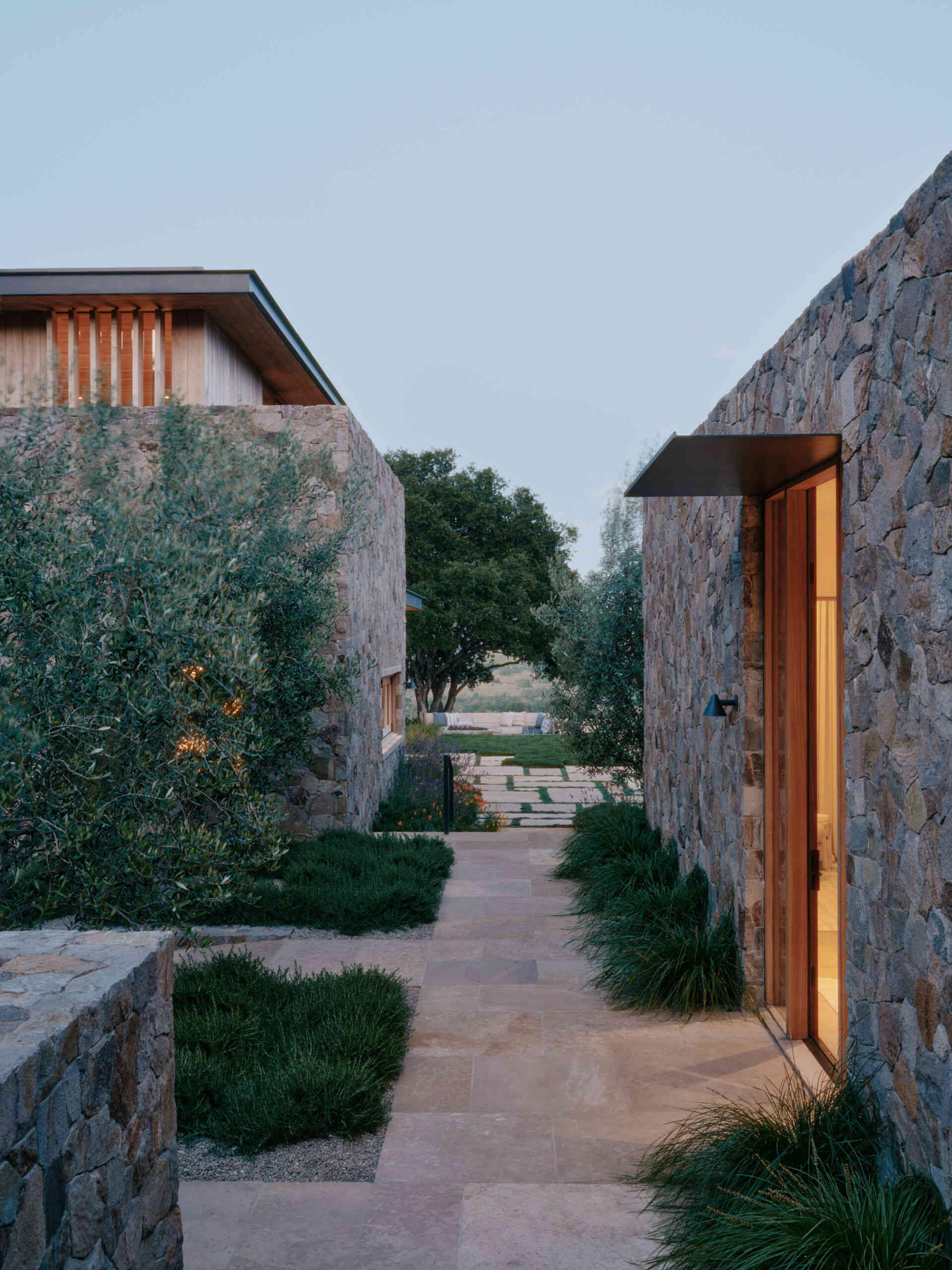 Stone pathways and drought-tolerant landscaping connect the pavilions of this California villa through gardens, courtyards, and hillside views.
