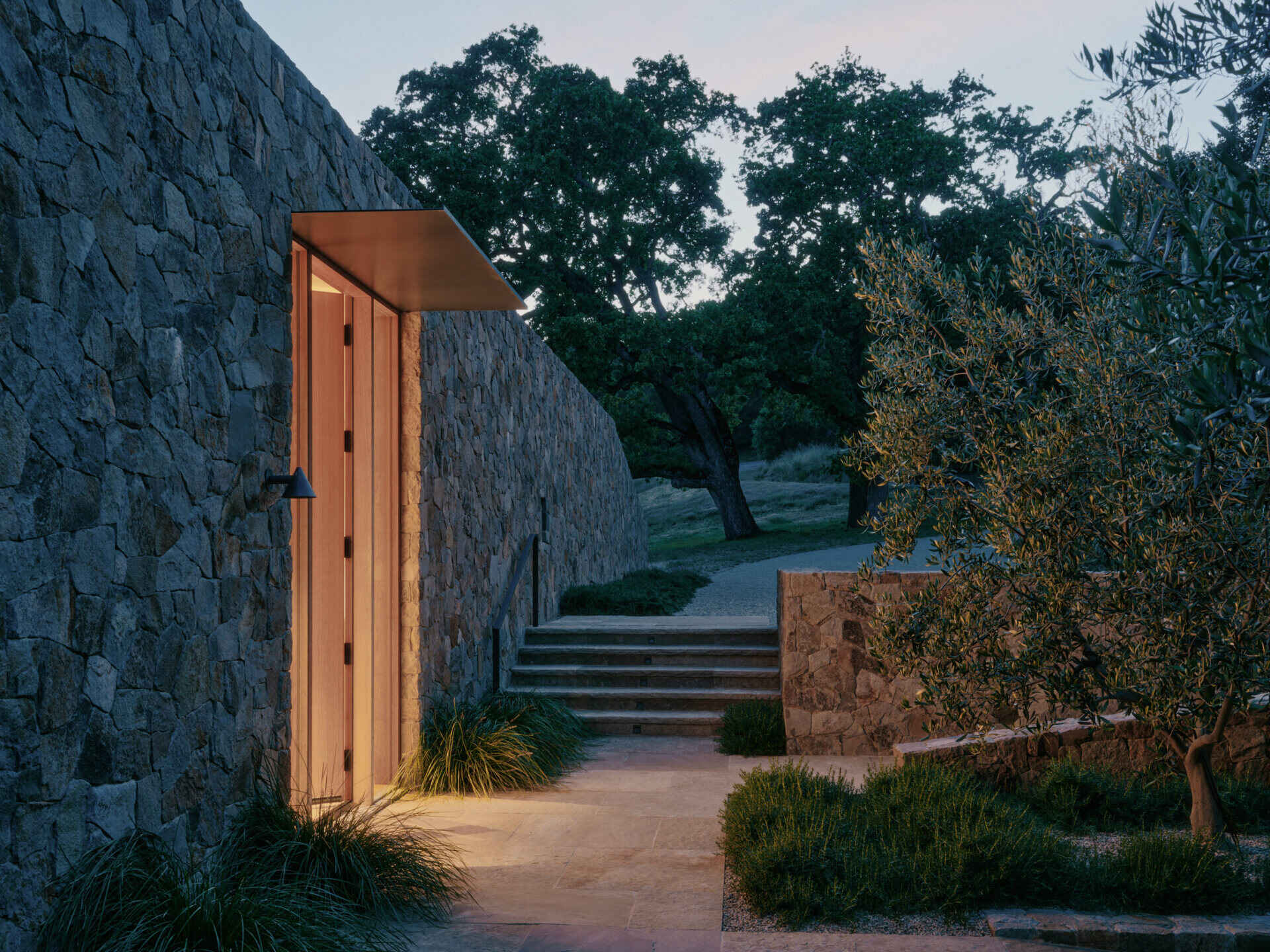 Stone pathways and drought-tolerant landscaping connect the pavilions of this California villa through gardens, courtyards, and hillside views.