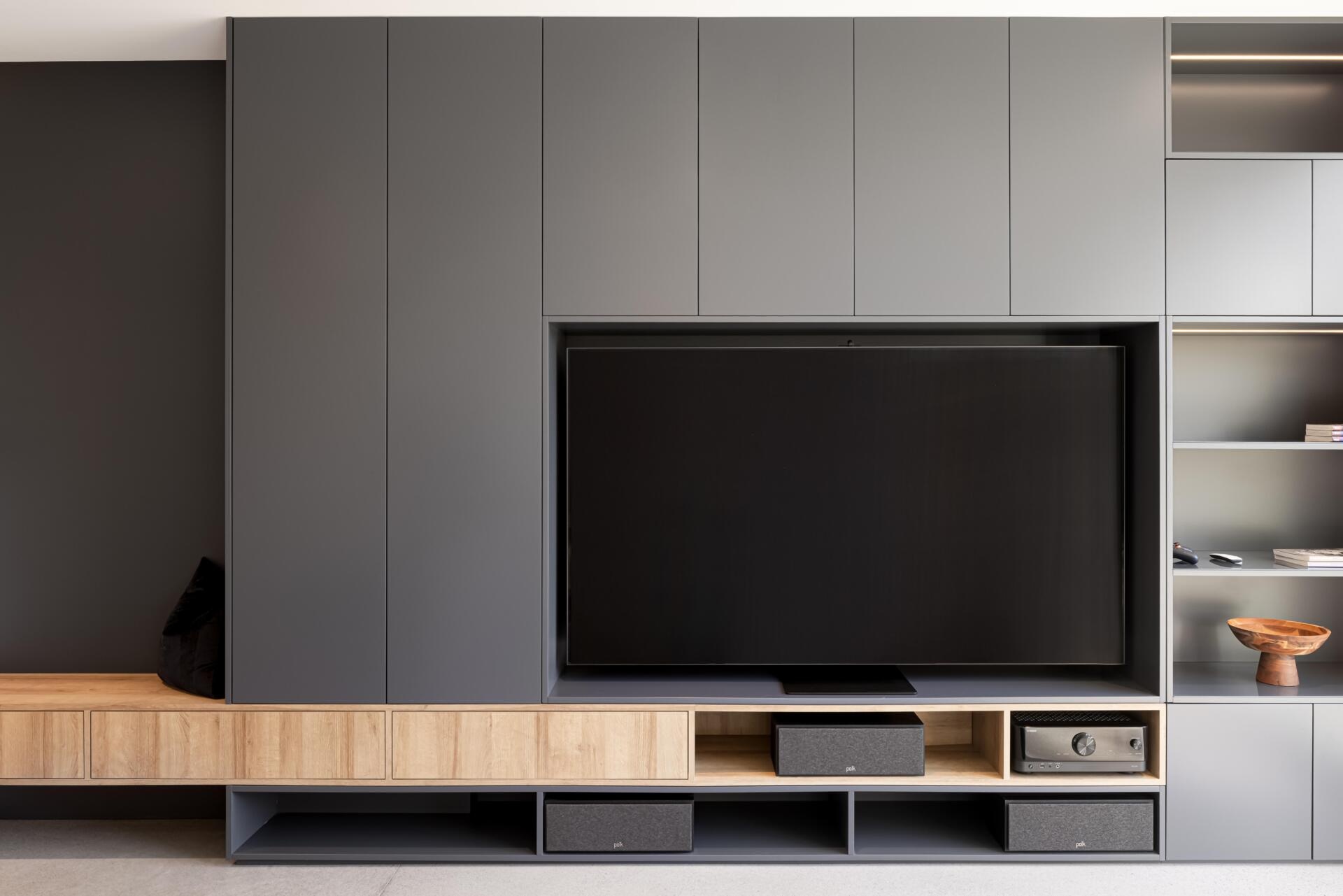 A warm and moody media room with built-in furniture and storage creates the perfect entertainment space inside this Québec mountain home.